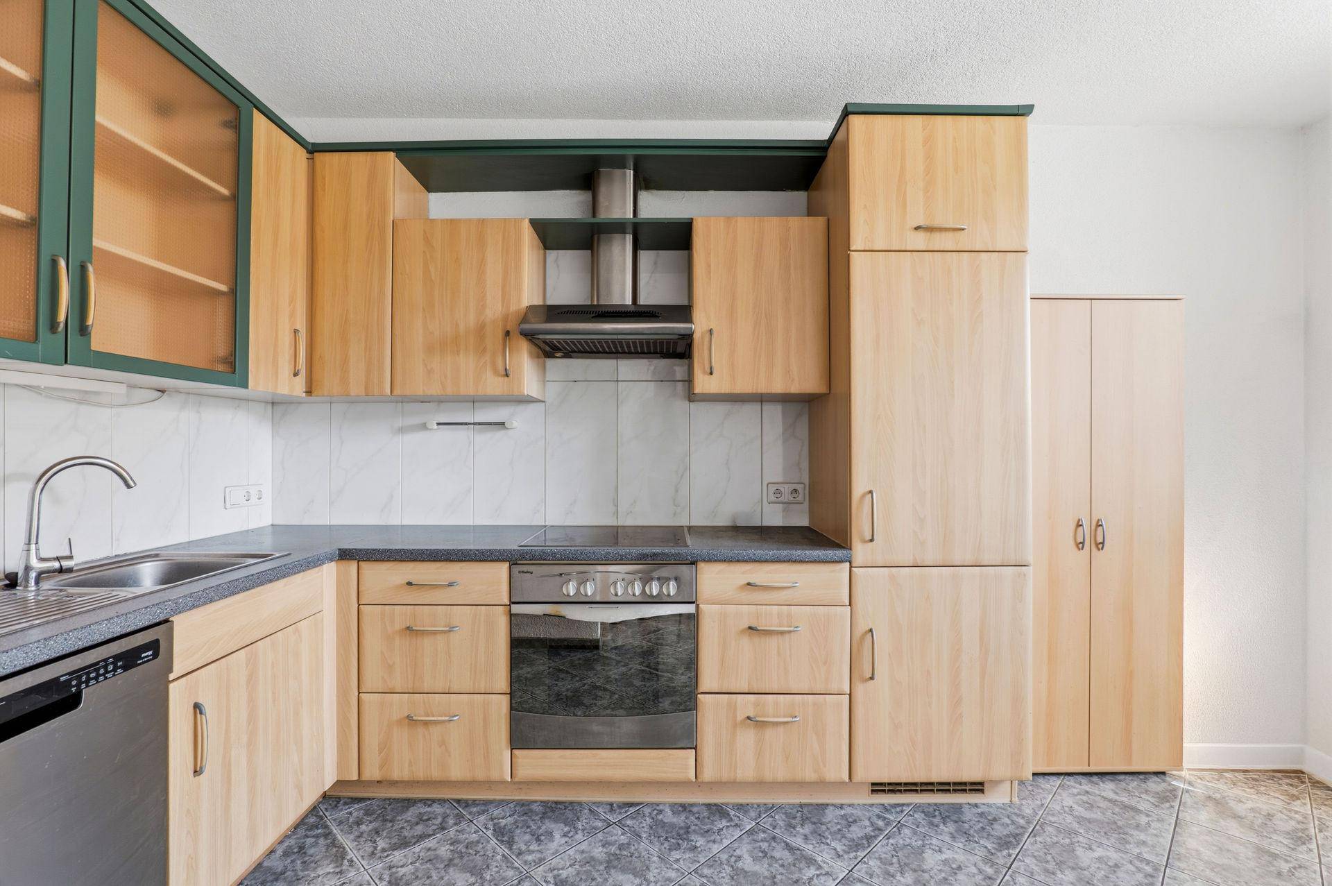 Küchenzeile mit Backofen, Dunstabzugshaube und hellen Holzschränken.