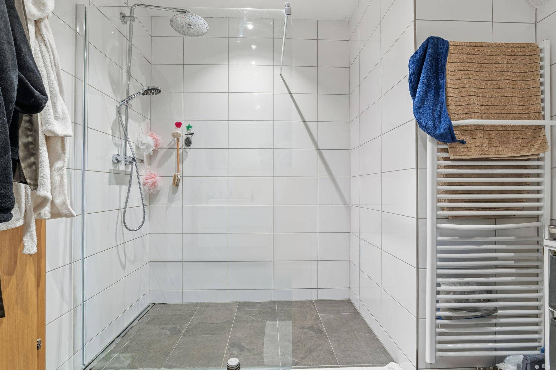Modernes Badezimmer mit großer begehbarer Dusche und beheiztem Handtuchhalter.