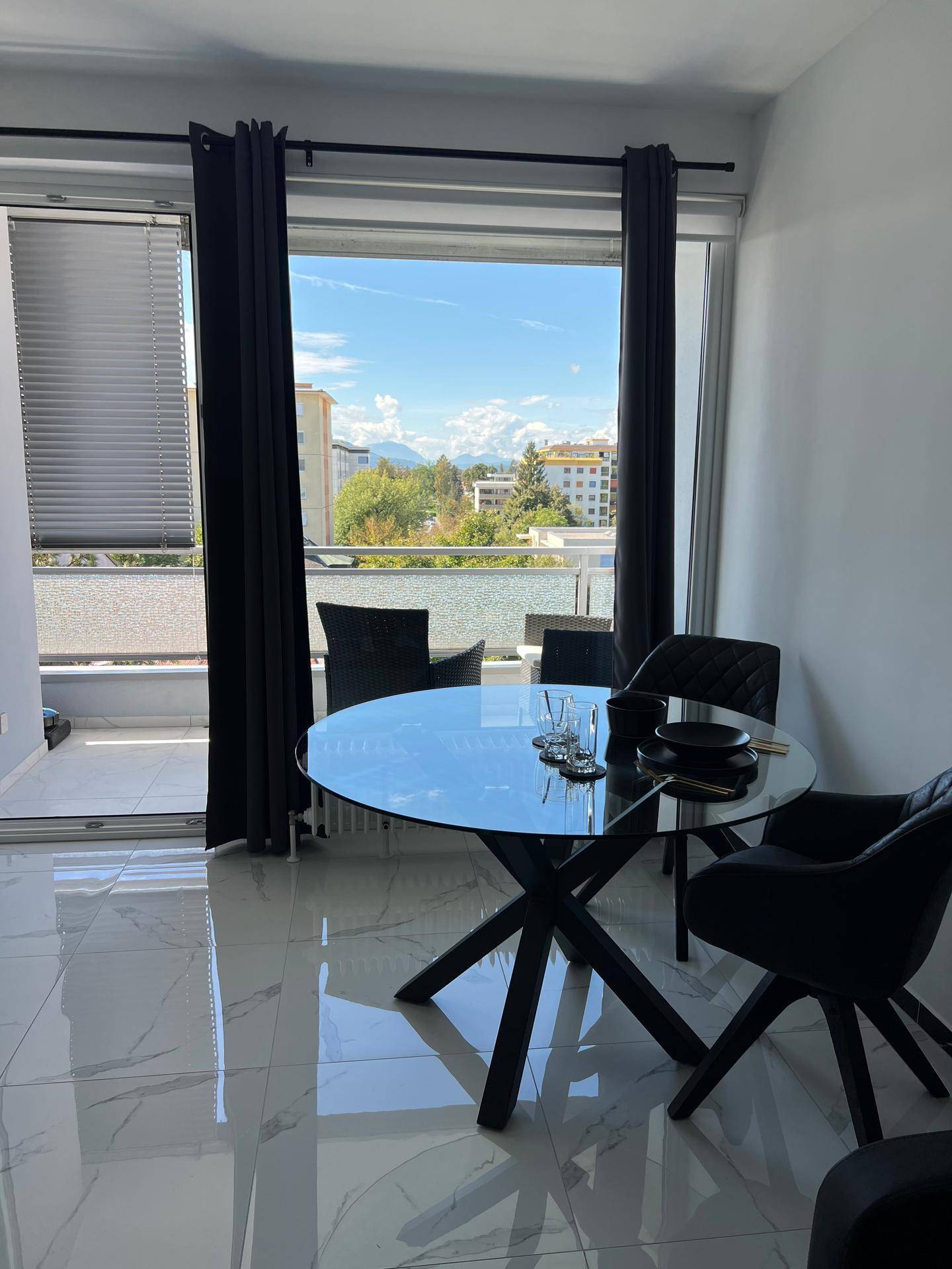 Heller Wohn- und Essbereich mit modernem Glastisch und Zugang zum Balkon mit Bergblick.