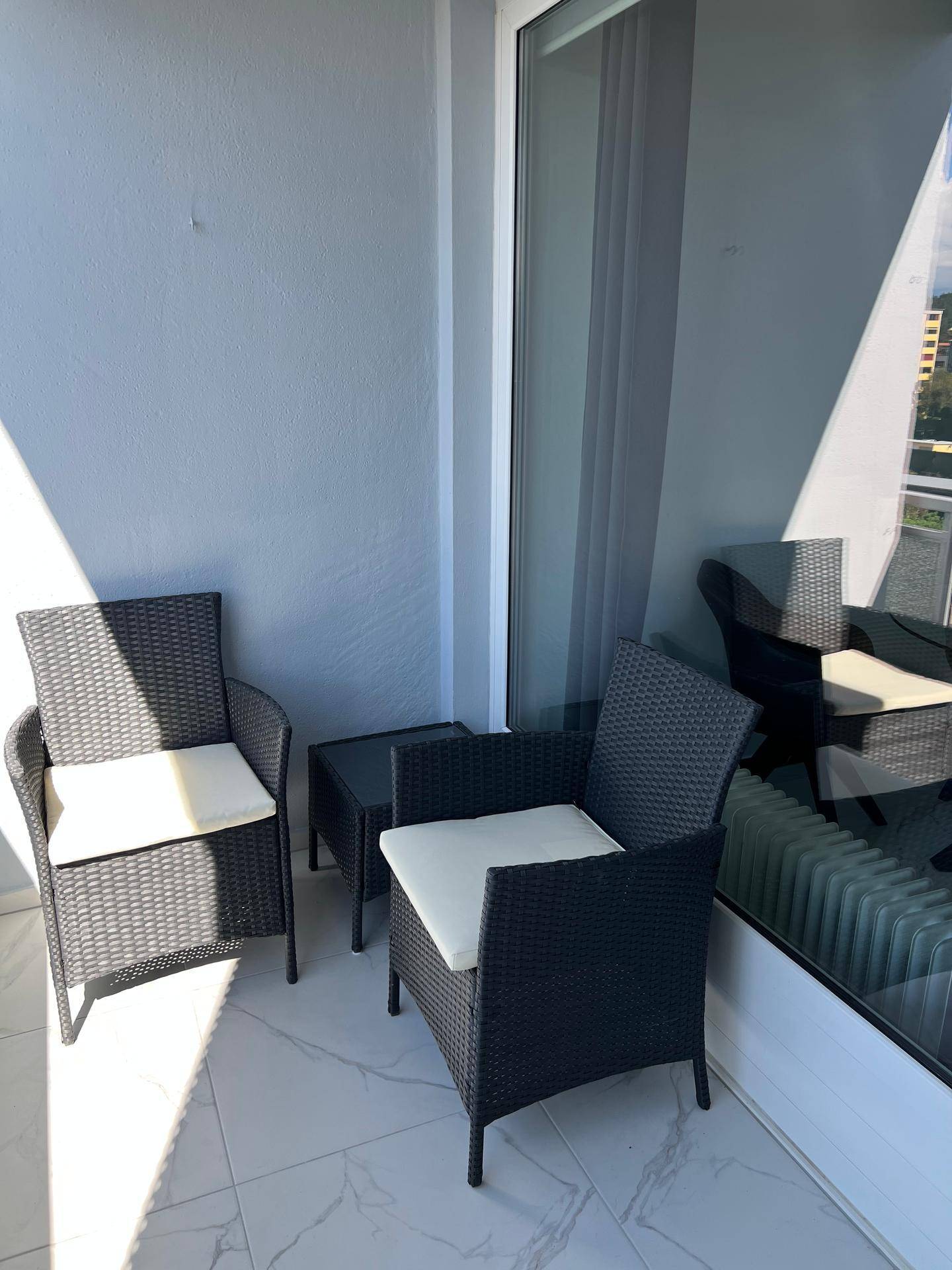 Gemütlicher Balkon mit Rattanmöbeln und Fliesenboden, ideal zum Entspannen im Freien.