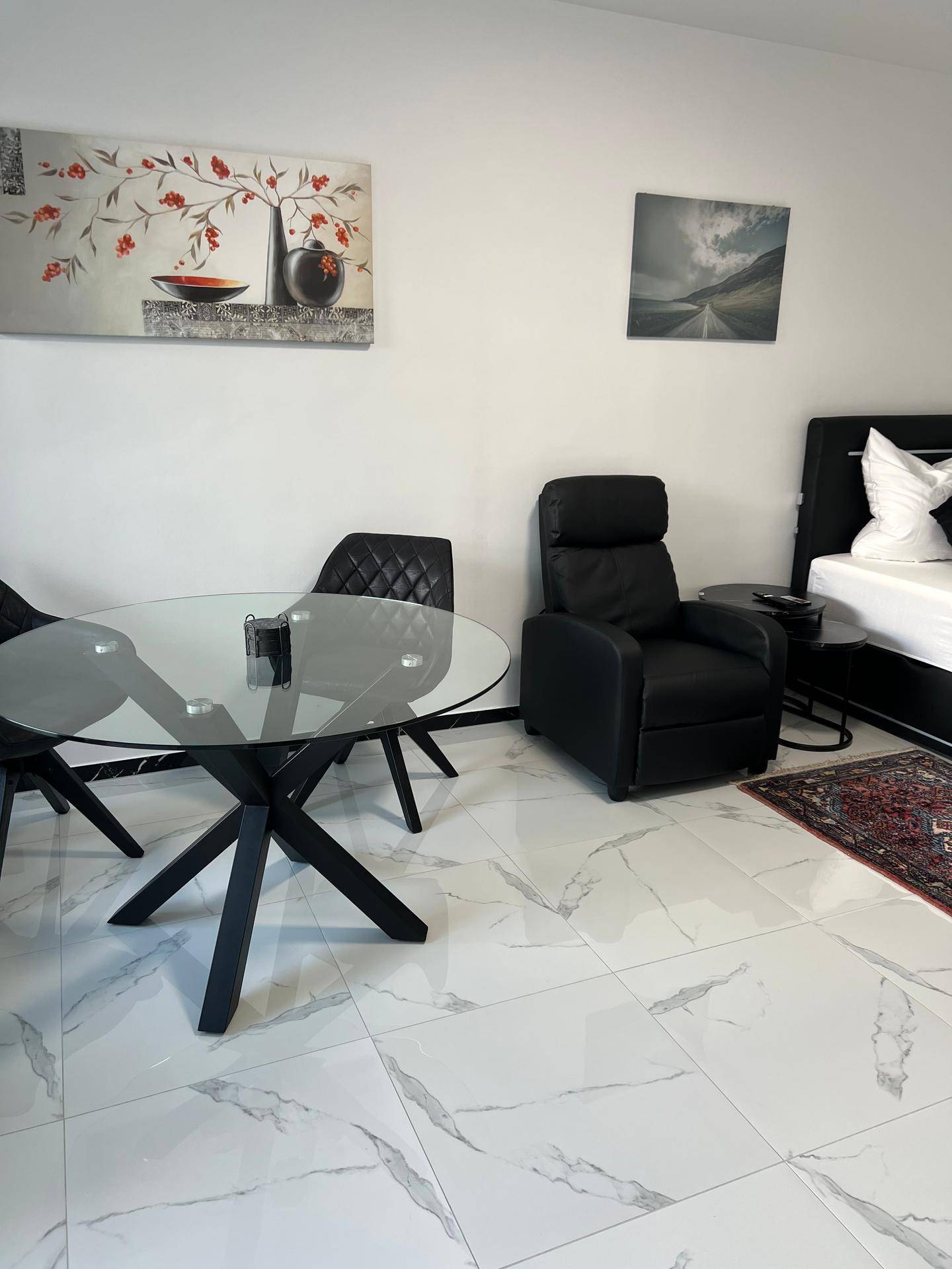 Gemütlicher Sessel und Esstisch in einem hellen Wohnbereich mit moderner Kunst an der Wand.
