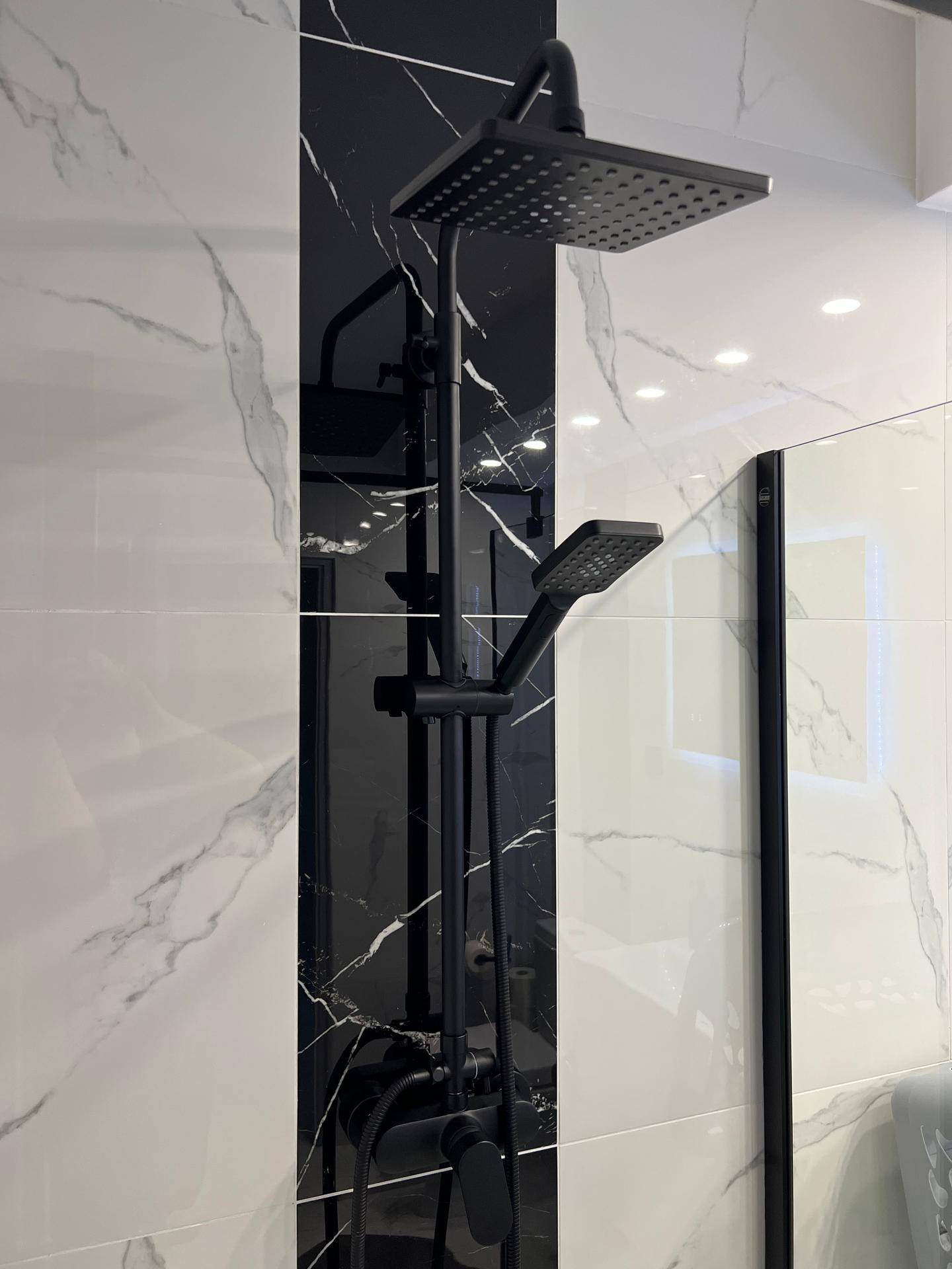 Detailansicht der modernen Regendusche mit schwarzer Armatur und eleganten Marmorfliesen.
