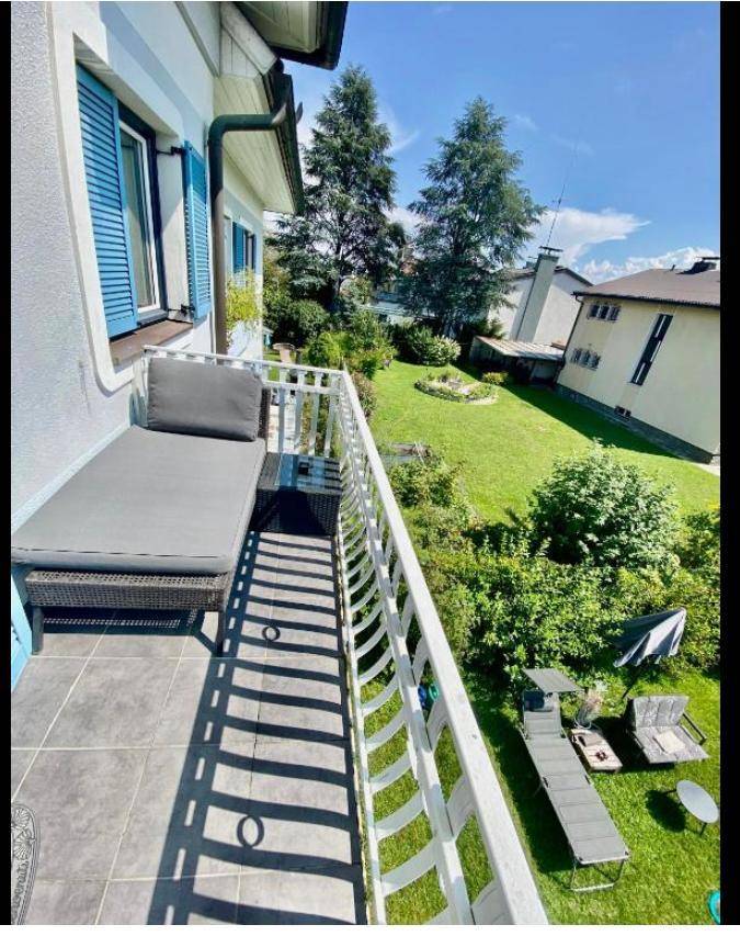 Balkon mit blauen Fensterläden, Liege und Blick auf den weitläufigen Garten.