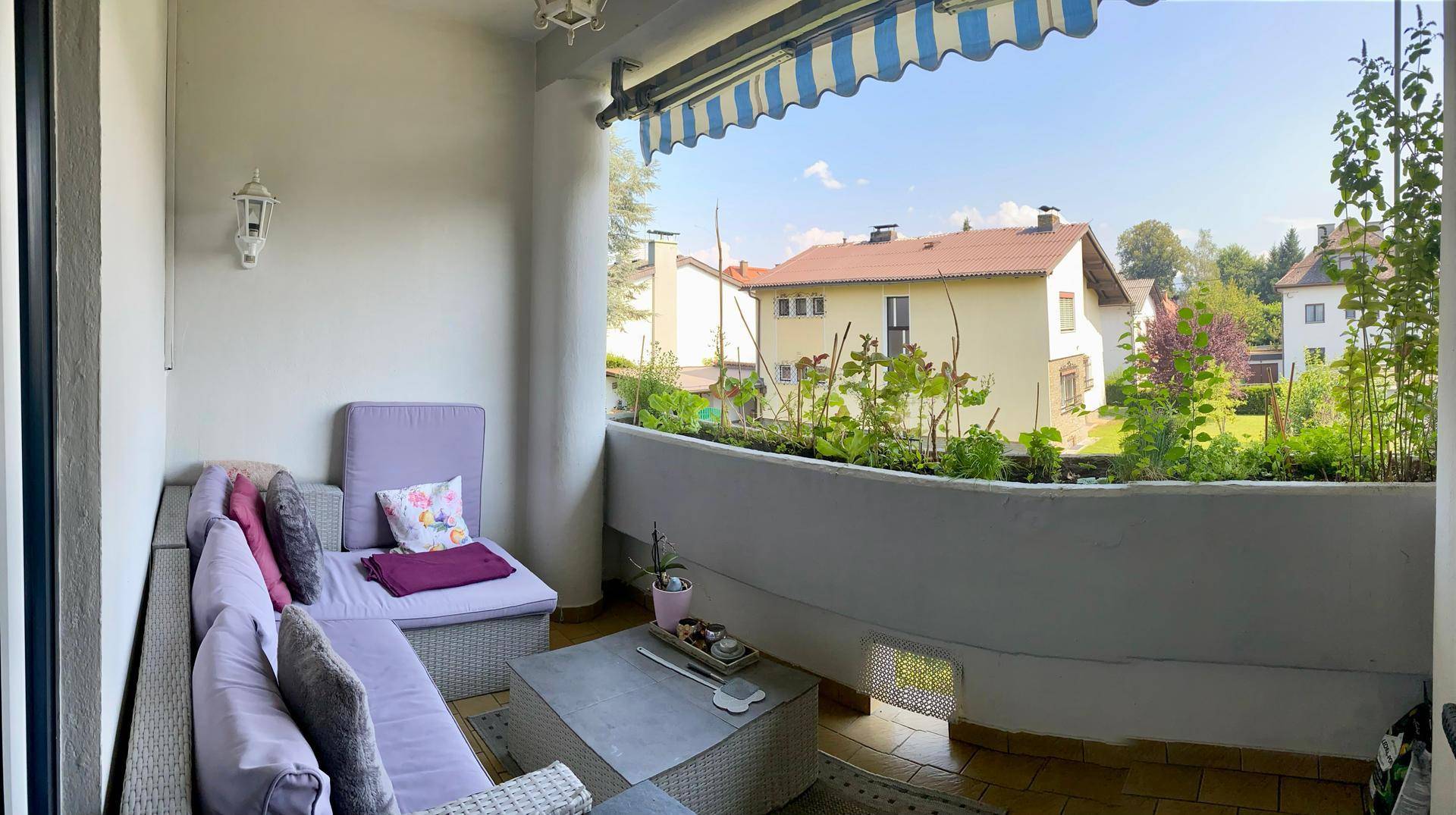 Gemütlicher Balkon mit Sitzgelegenheiten, Pflanzen und Markise, ideal zum Entspannen.