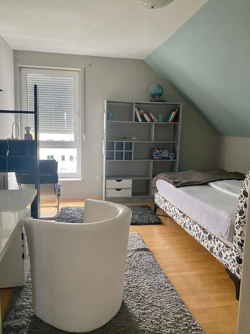 Schlafzimmer im Dachgeschoss mit Bett, Schreibtisch und schräger Decke.