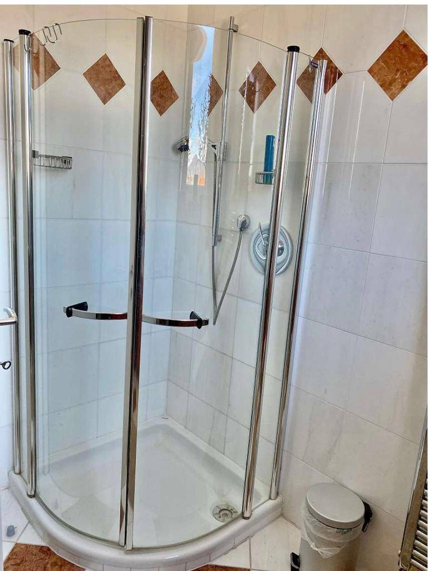 Duschkabine im Badezimmer mit Fliesen in Weiß und Braun, sauber und funktional.