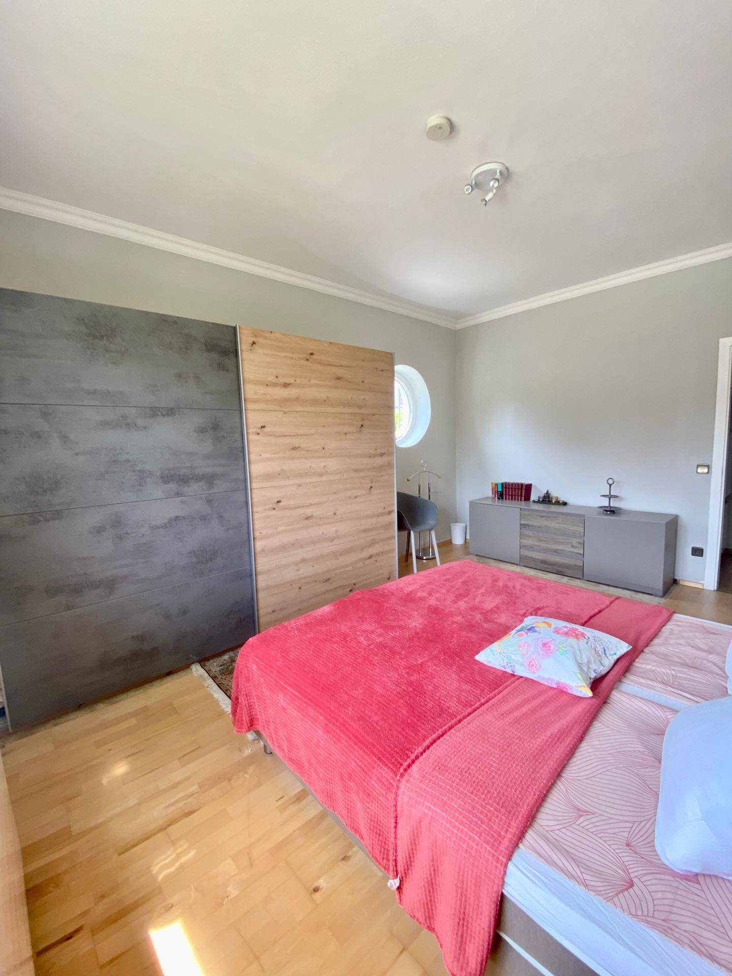 Geräumiges Schlafzimmer mit Holzboden, Doppelbett und modernem Kleiderschrank.