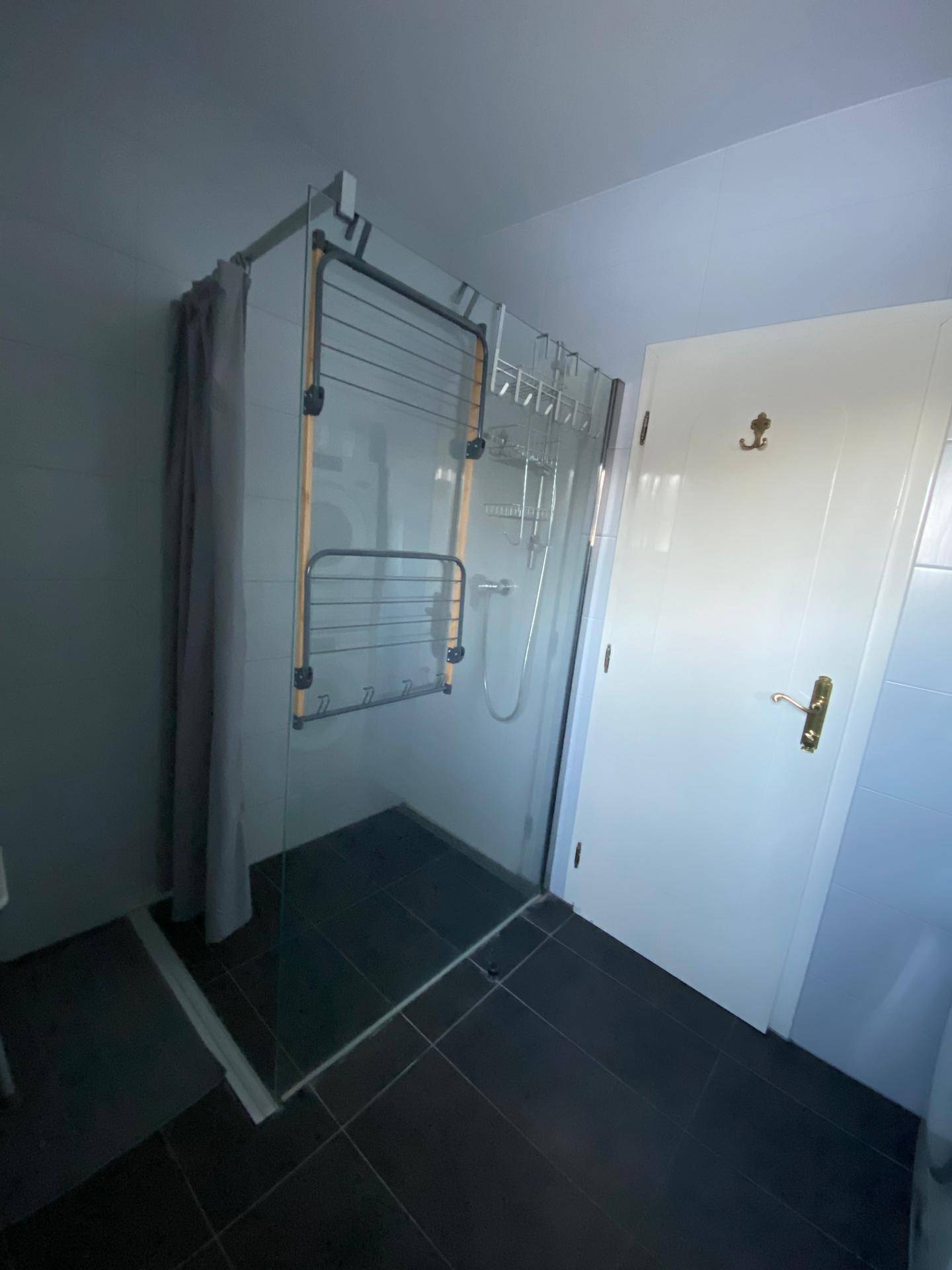Badezimmer mit geräumiger Dusche und einem praktischen Wäscheständer, hell gefliest.