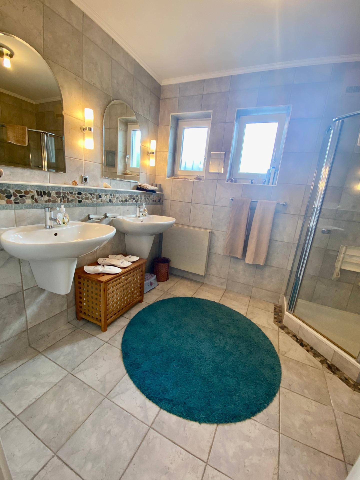 Geräumiges Badezimmer mit Doppelwaschbecken, Dusche und Fliesenboden.