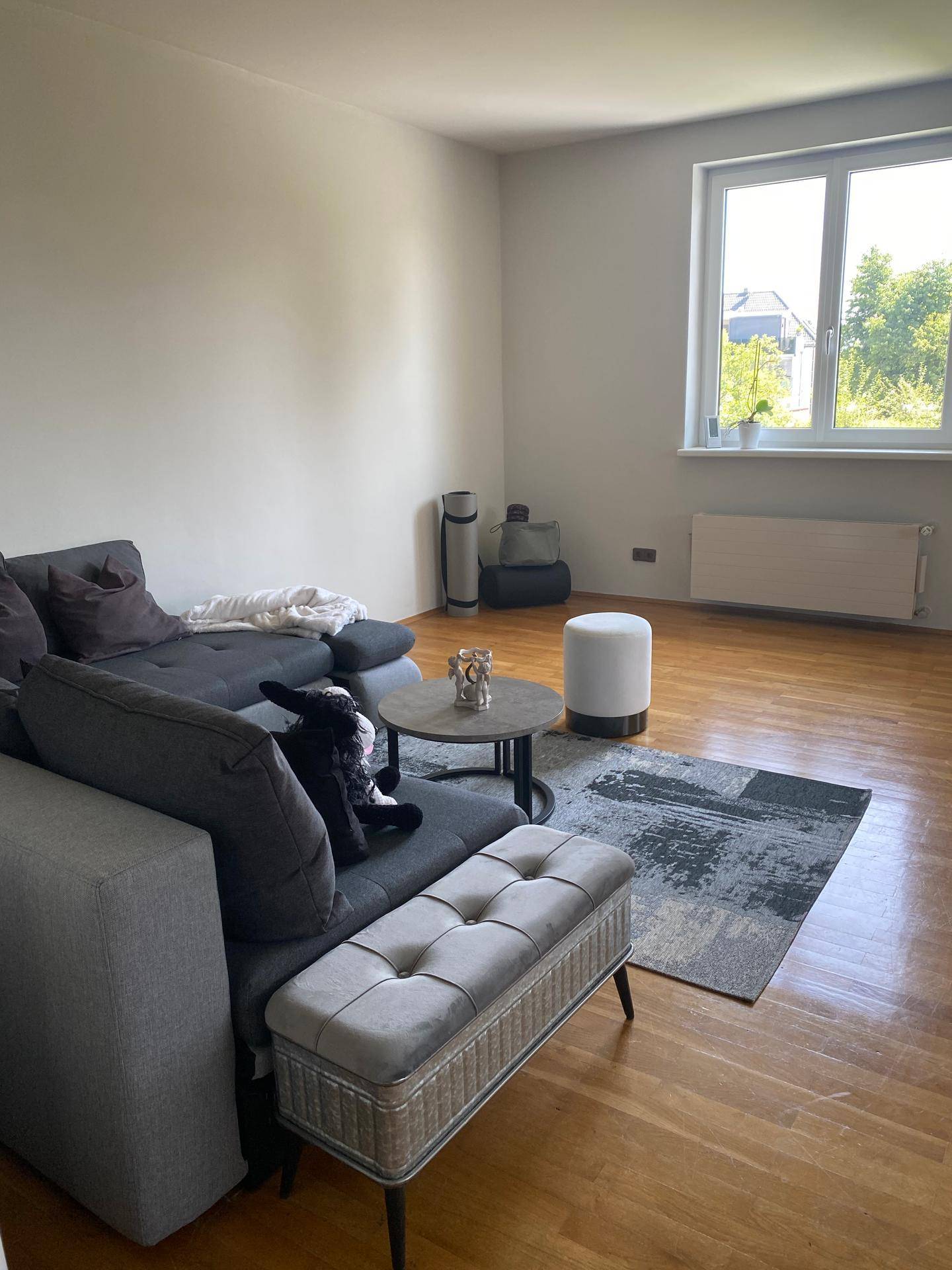 Modernes Wohnzimmer mit großem Sofa, Holzboden und Fenster für viel Tageslicht.