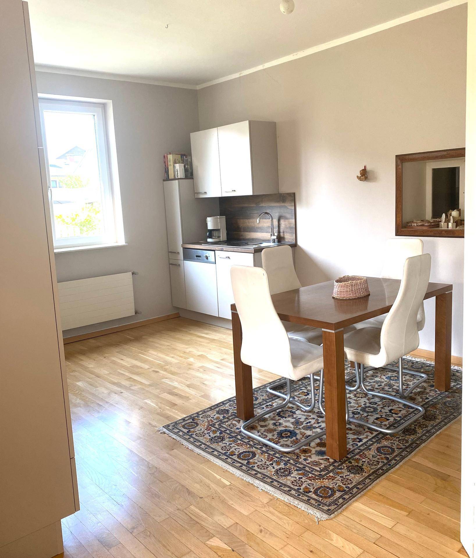 Kompakte Küche mit Essbereich, Holzboden und Fenster für natürliches Licht.