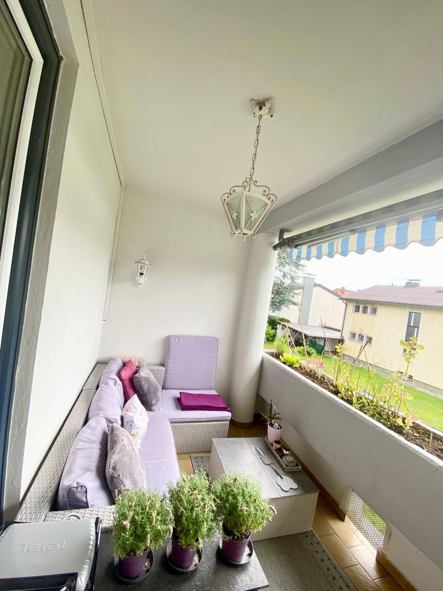 Gemütlicher Balkon mit Lounge-Möbeln, Pflanzen und Blick ins Grüne.