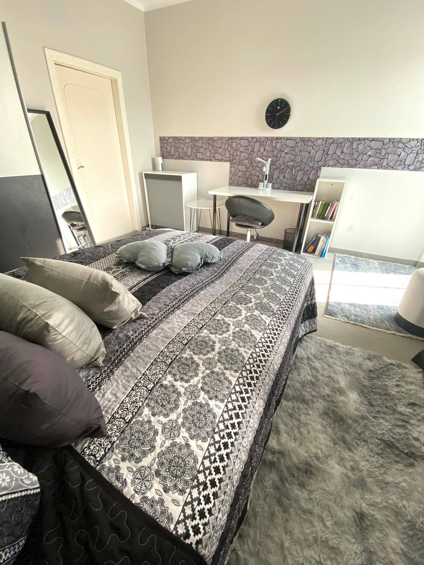 Schlafzimmer mit Doppelbett, Schreibtisch und modernem Kleiderschrank.