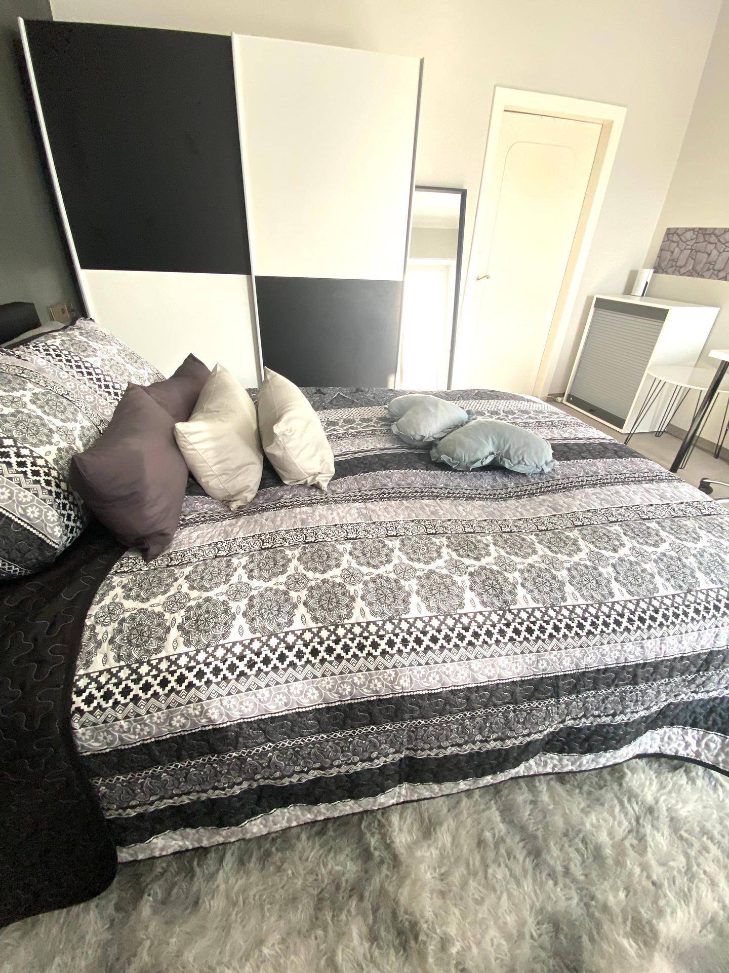 Schlafzimmer mit Doppelbett, gemustertem Teppich und modernem Kleiderschrank.