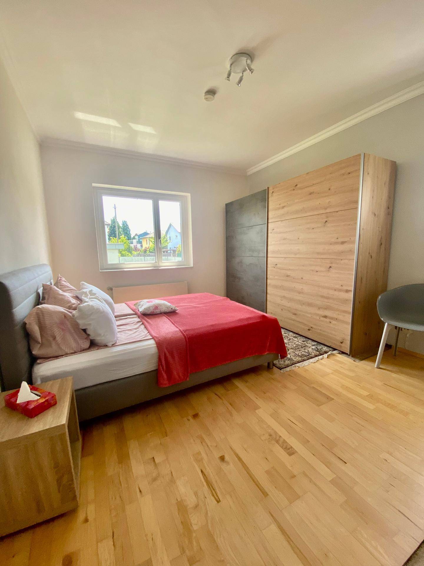 Schlafzimmer mit Holzboden, Doppelbett und großem Schrank mit Schiebetüren.