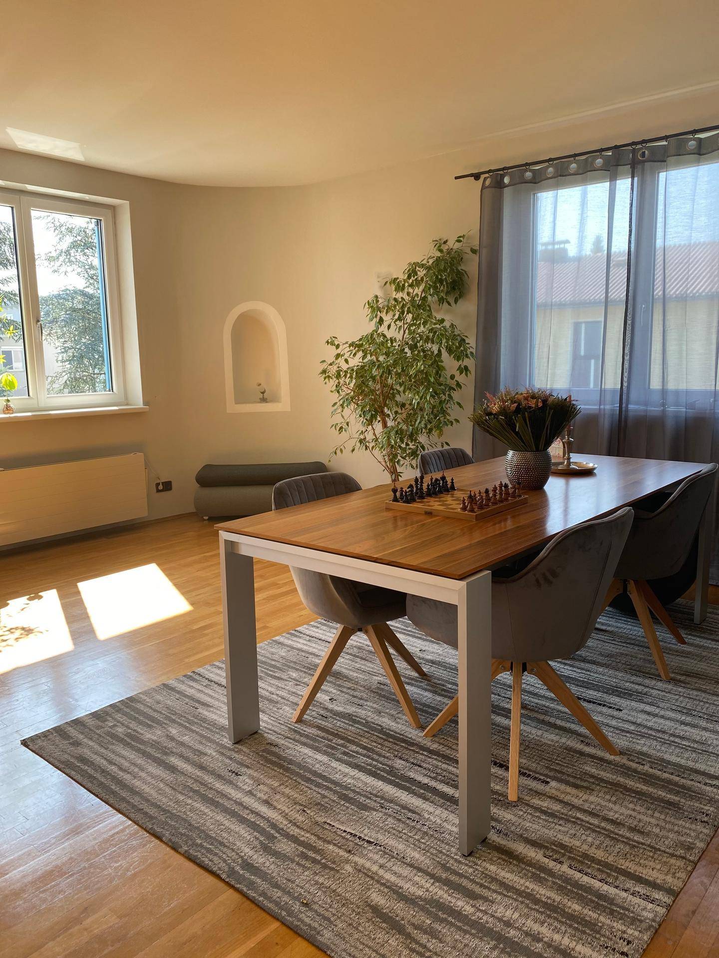 Essbereich mit Holztisch, modernen Stühlen und Fenster mit Blick ins Grüne.