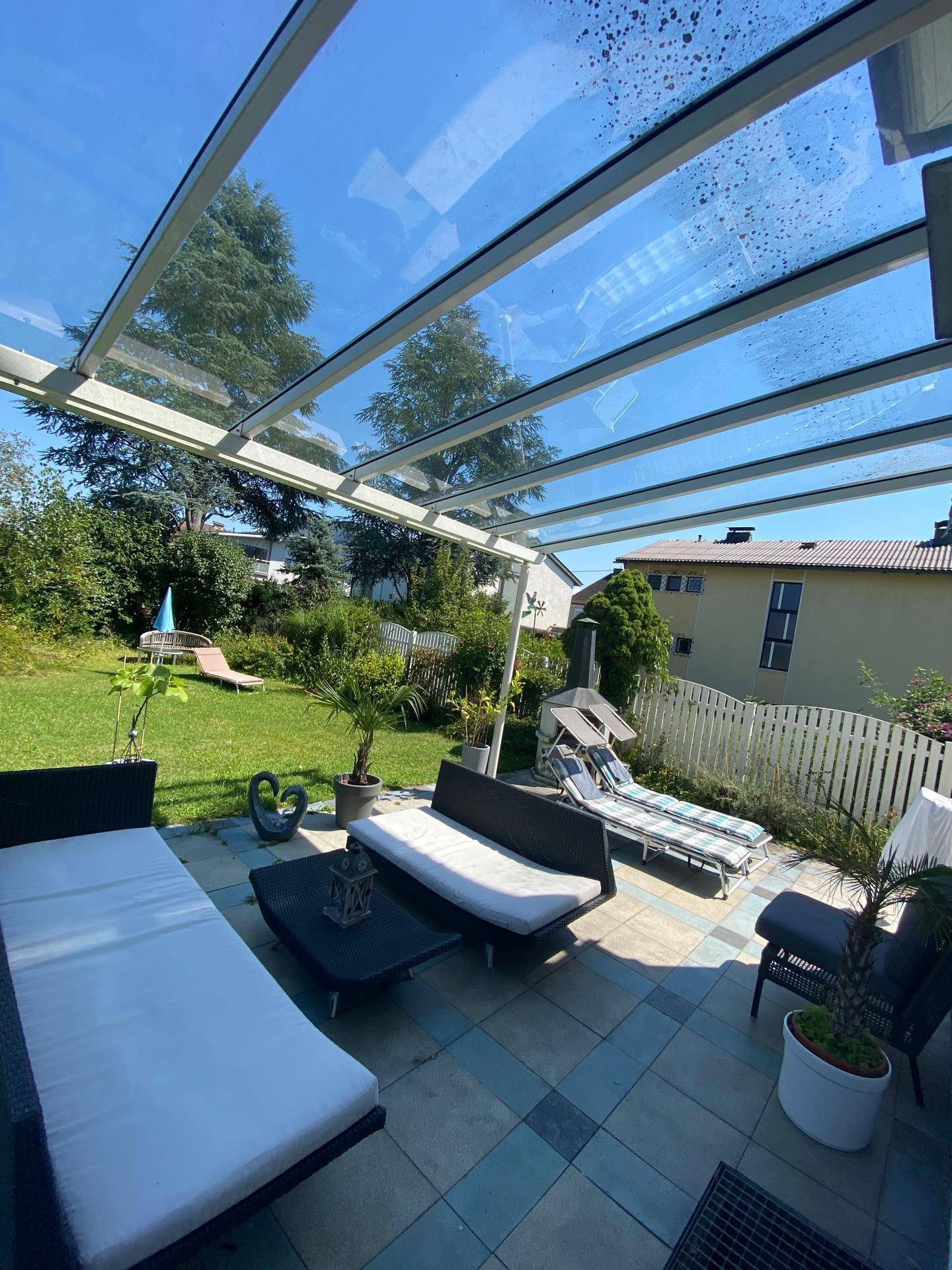 Großzügige überdachte Terrasse mit Lounge-Möbeln und Blick auf den Garten.