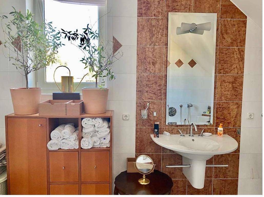 Badezimmer mit Waschbecken, großem Spiegel und Fenster für natürliches Licht.
