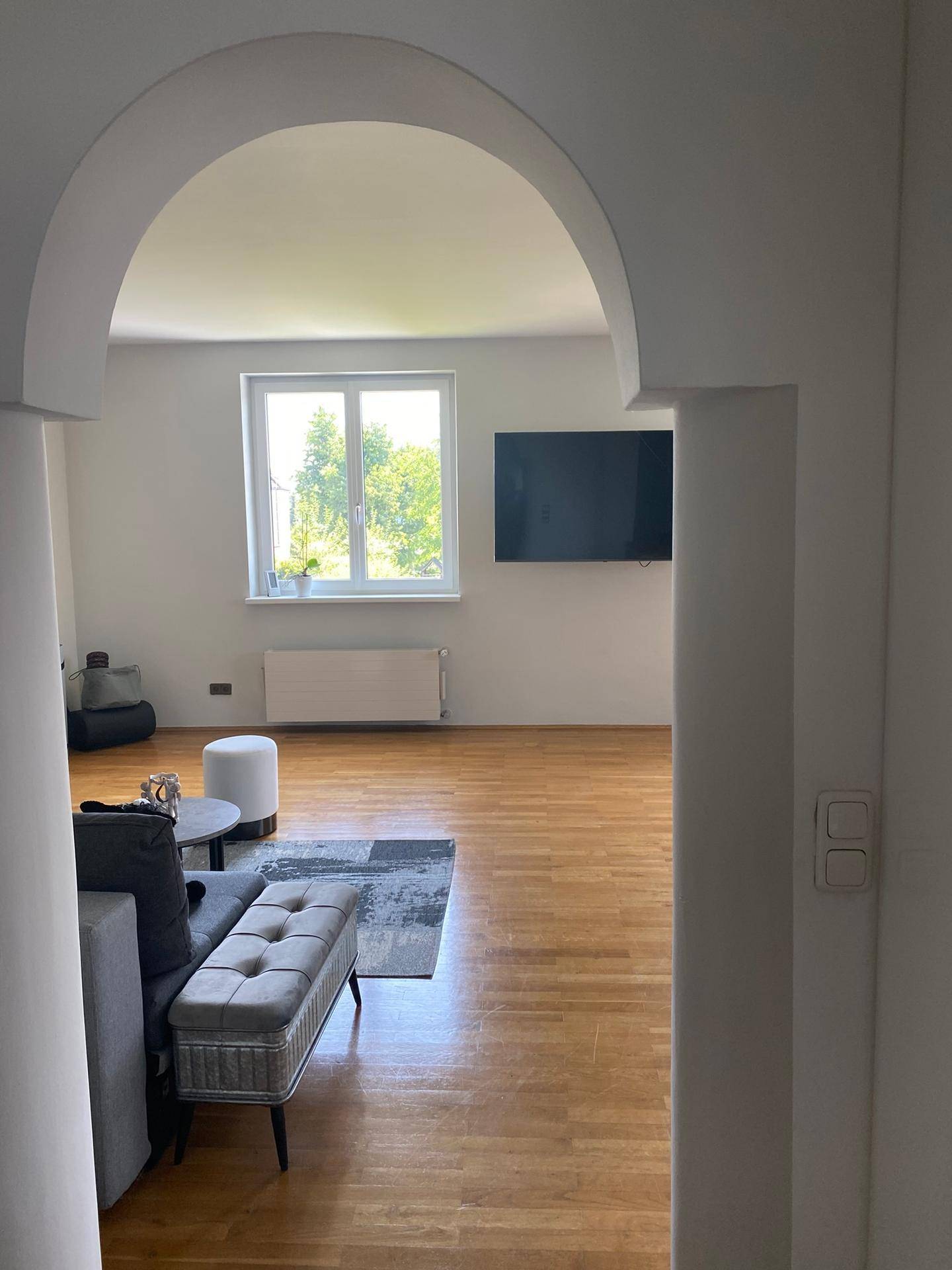 Heller Flurbereich mit Holzboden und eleganten Bögen, der zu weiteren Räumen führt.