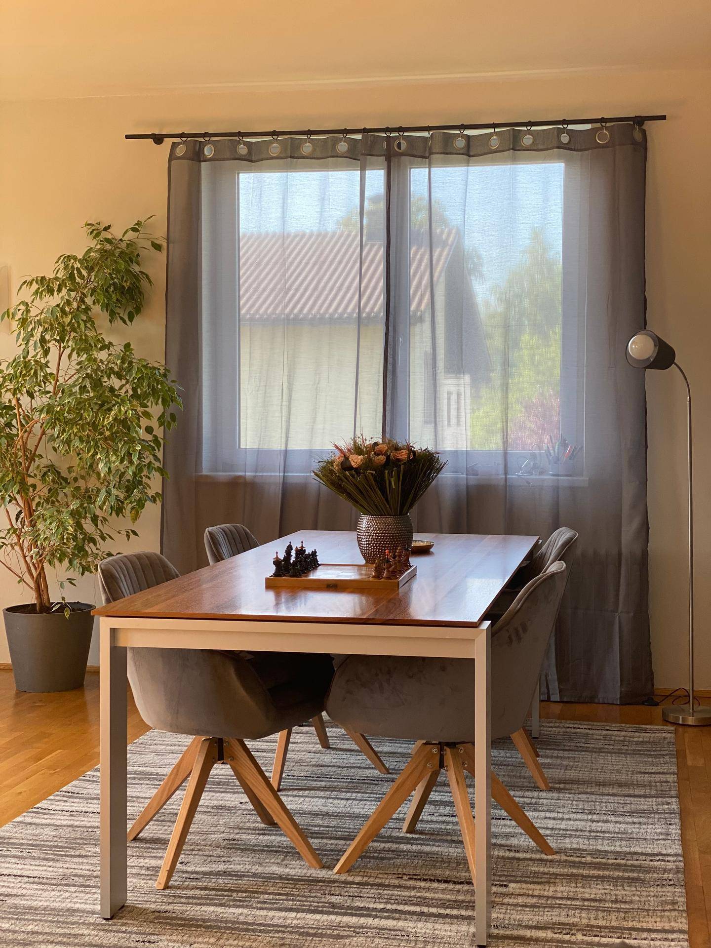 Heller Essbereich mit Holztisch, modernen Stühlen und Vorhängen am Fenster.