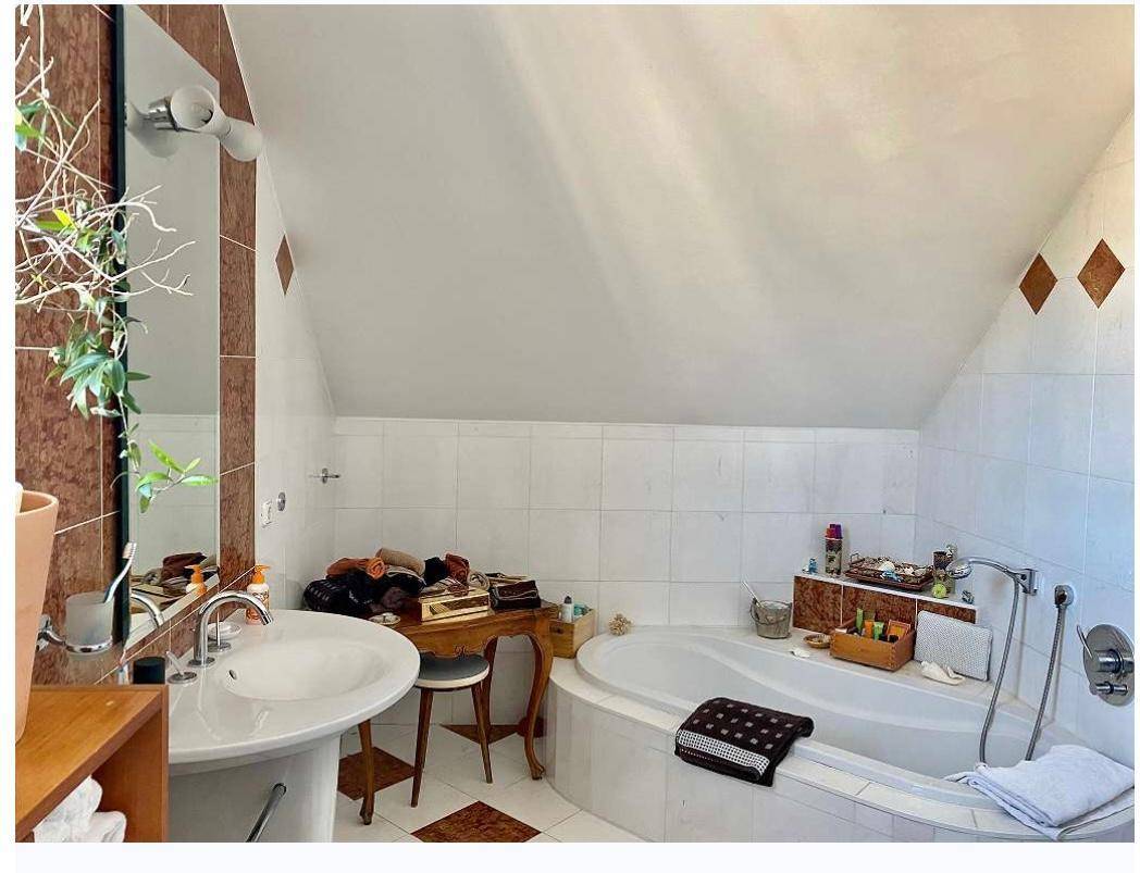 Badezimmer im Dachgeschoss mit Badewanne, Waschbecken und schräger Decke.