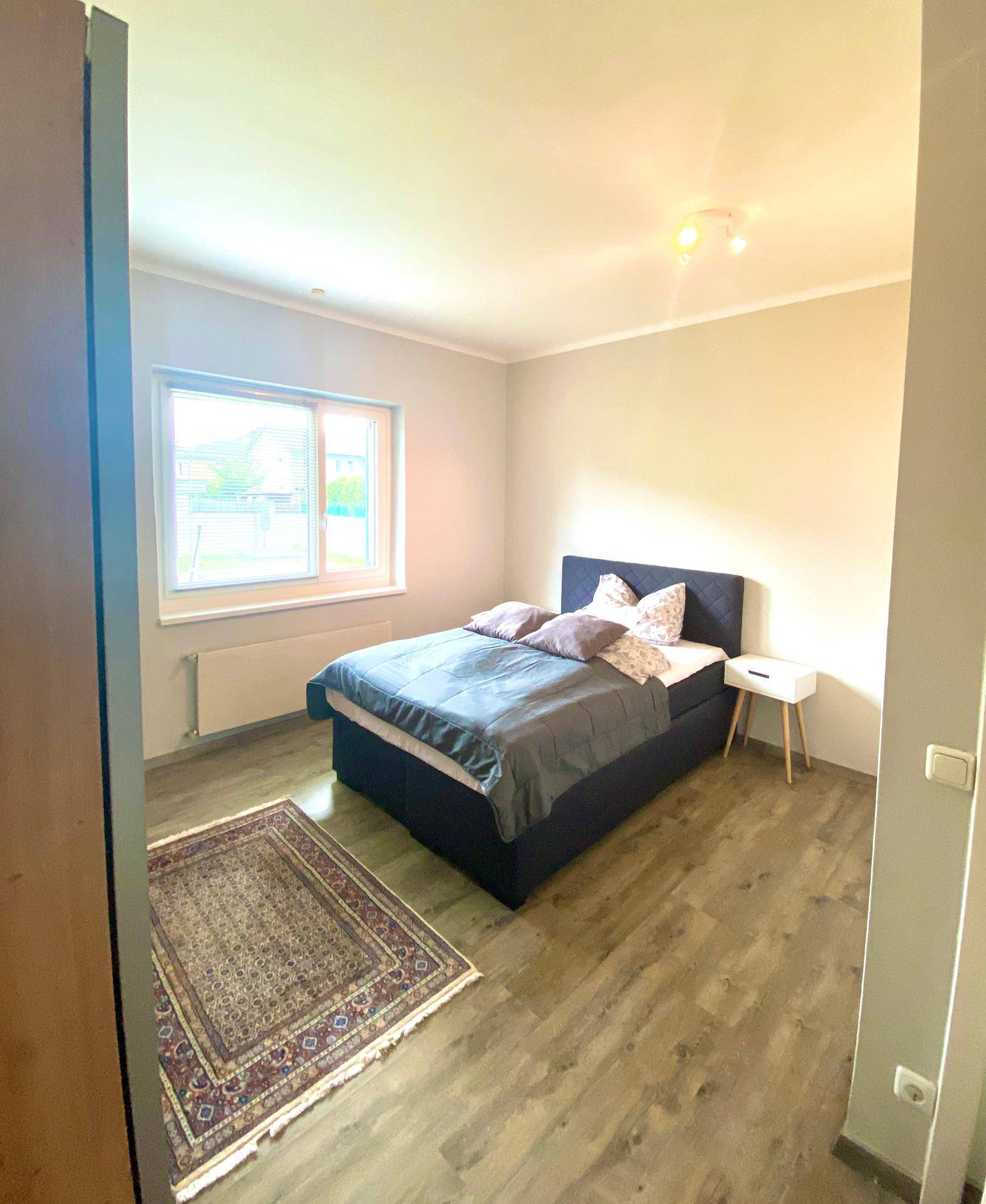Helles Schlafzimmer mit Doppelbett, Schrank und Fenster für viel Tageslicht.