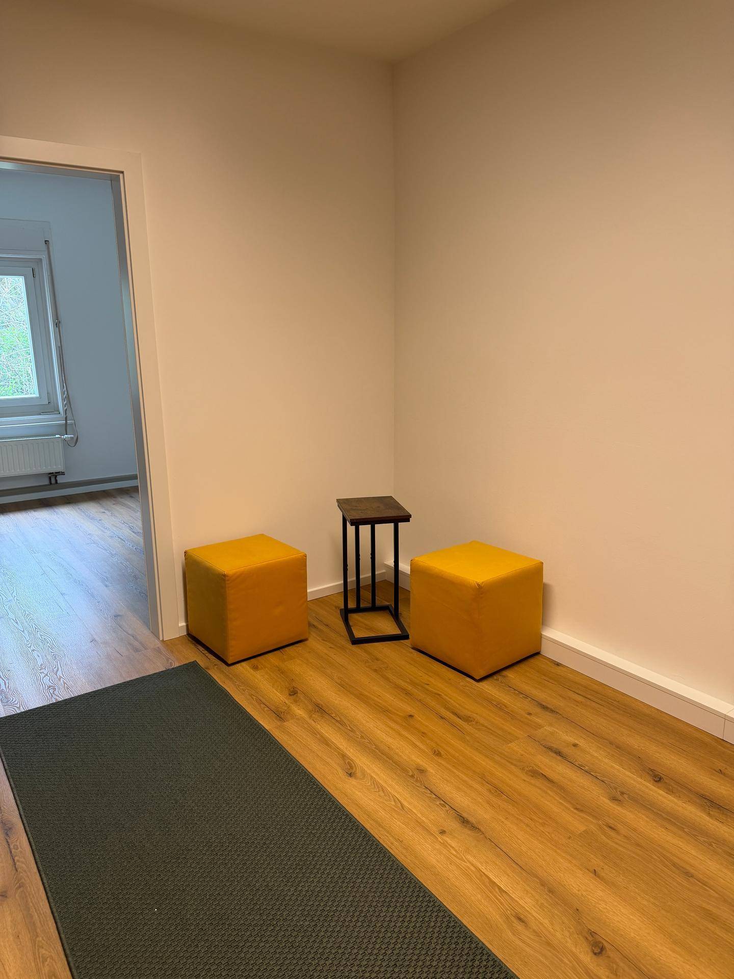 Heller Flur mit Laminatboden, gelben Hockern und einem kleinen Beistelltisch als Dekoration.