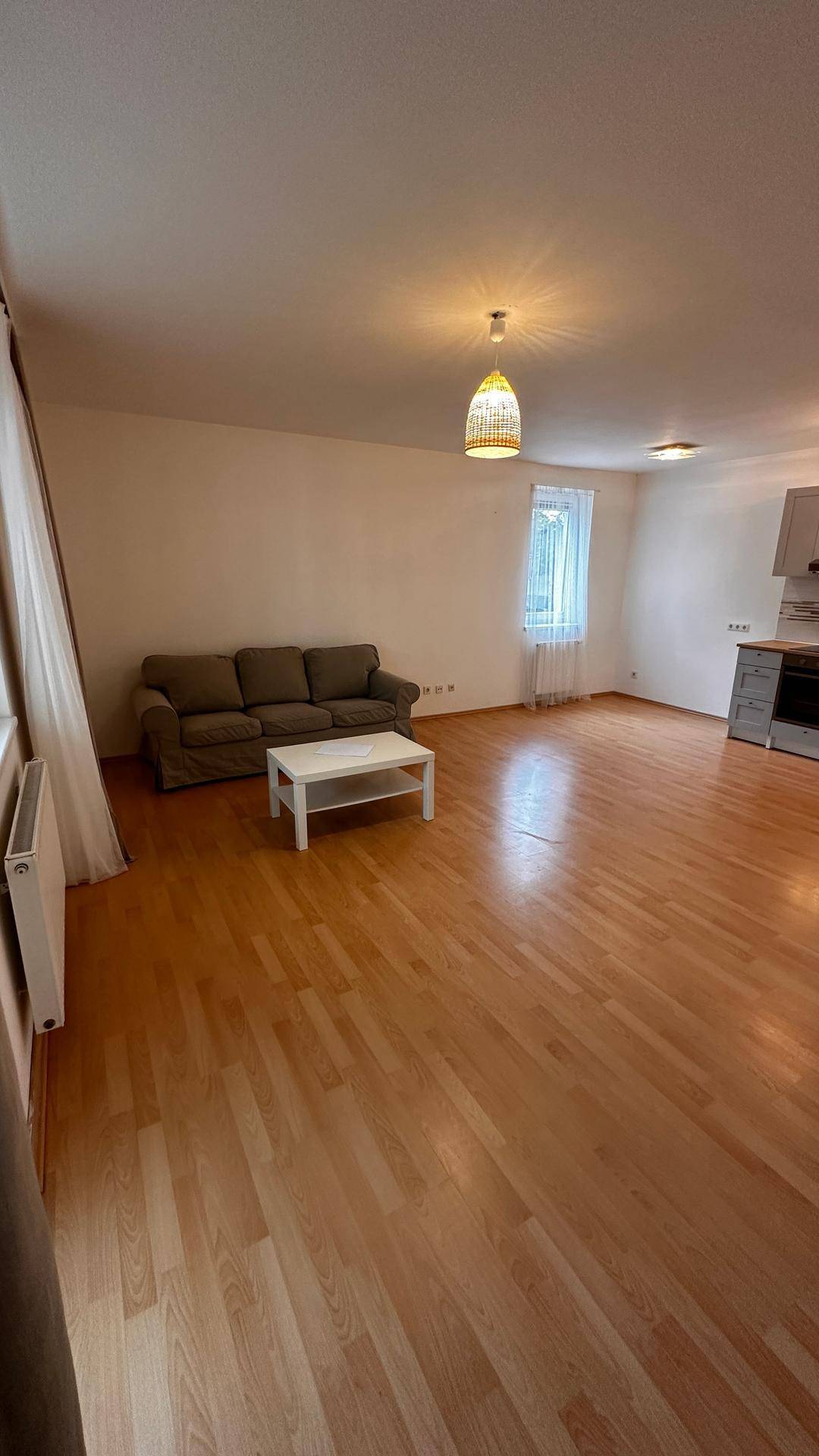 Geräumiger Wohnbereich mit beigem Sofa, Couchtisch und hellem Parkettboden.