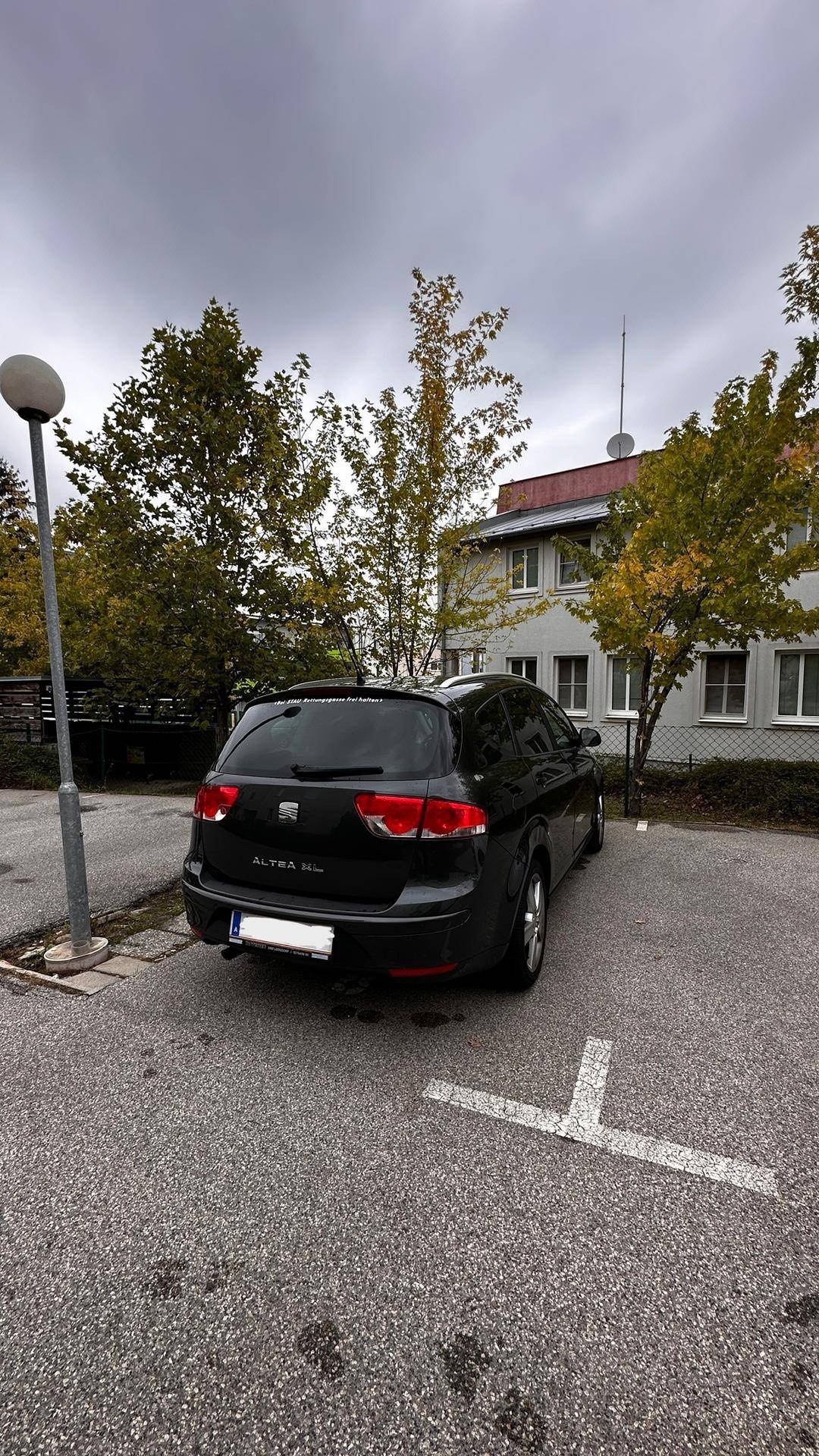 Außenparkplatz mit einem geparkten Auto vor dem Wohngebäude.