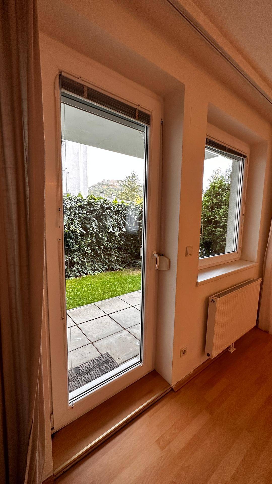 Große Fenstertür und Fenster bieten Blick ins Grüne und Zugang zum Außenbereich.