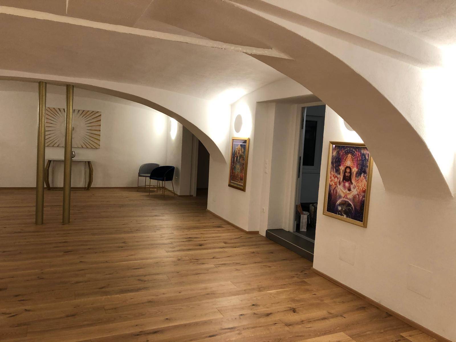 Heller Durchgangsbereich mit Holzboden, gewölbten Decken und dekorativen Bildern, der verschiedene Räume verbindet.