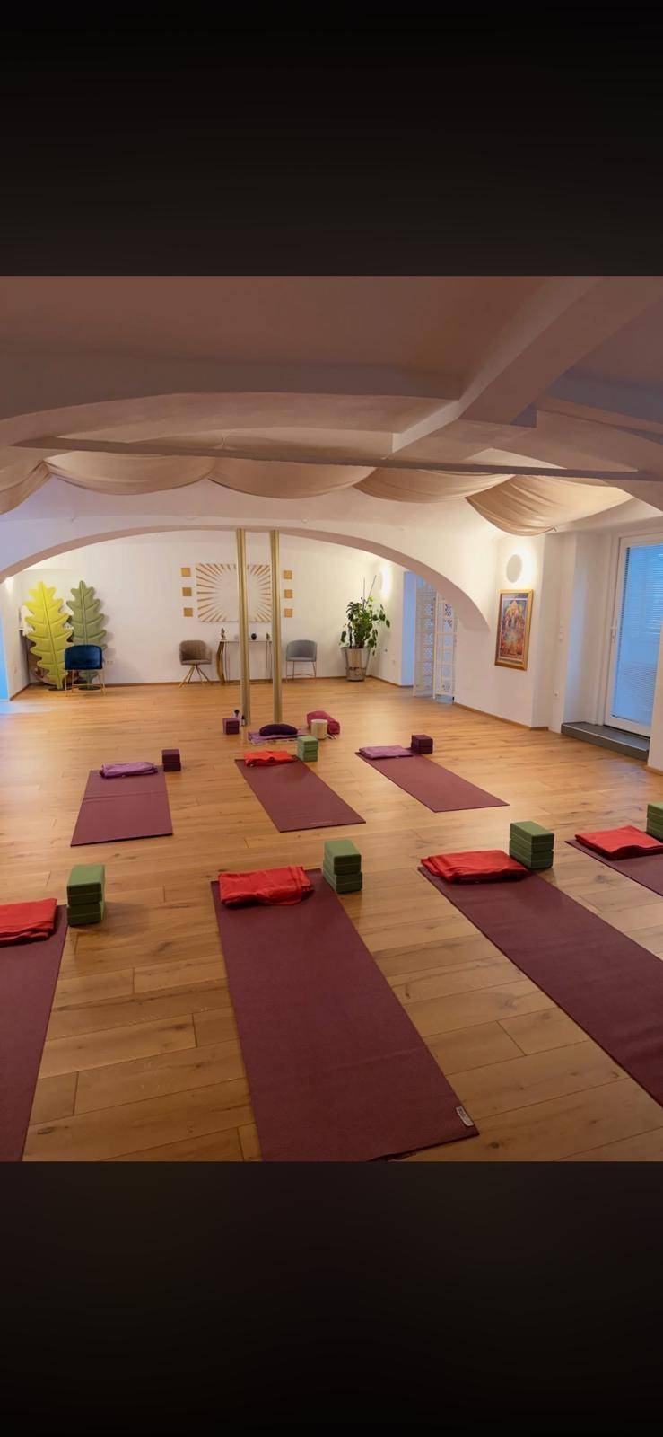 Geräumiges Yoga-Studio mit Holzboden, gewölbter Decke und Matten, ideal für Entspannung und Bewegung.