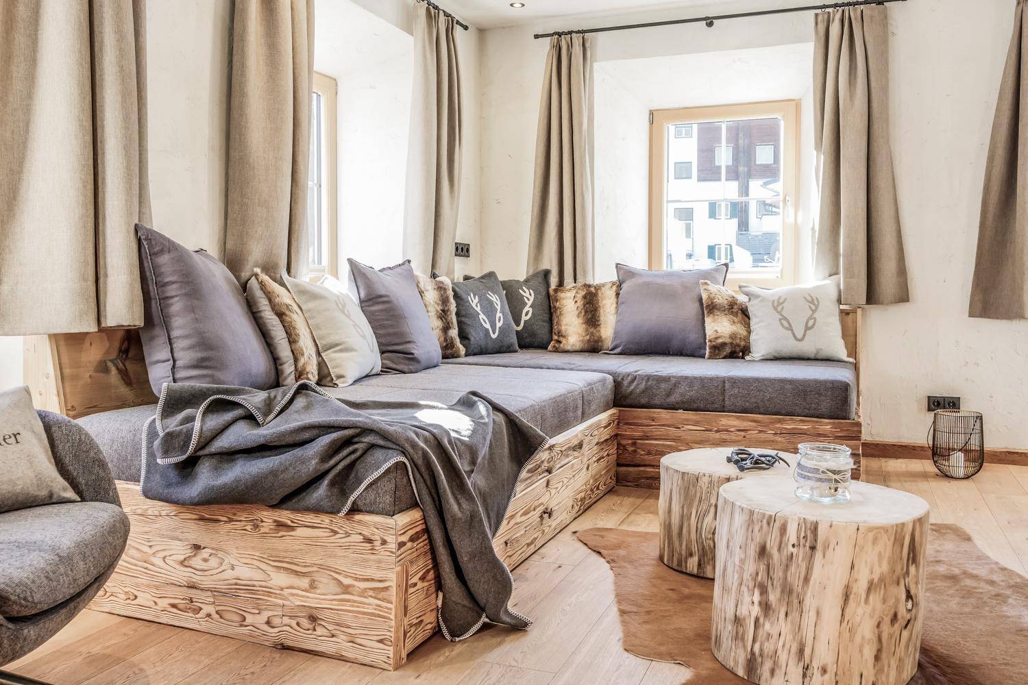 Geräumiges Wohnzimmer mit großem Ecksofa, rustikalen Holztischen und viel natürlichem Licht.