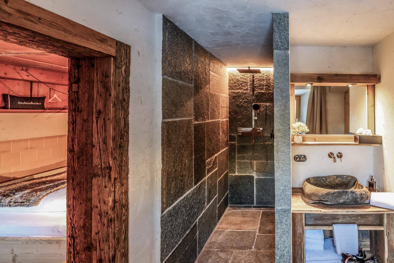 Modernes Badezimmer mit Natursteinwänden, begehbarer Dusche und rustikalem Steinwaschbecken.