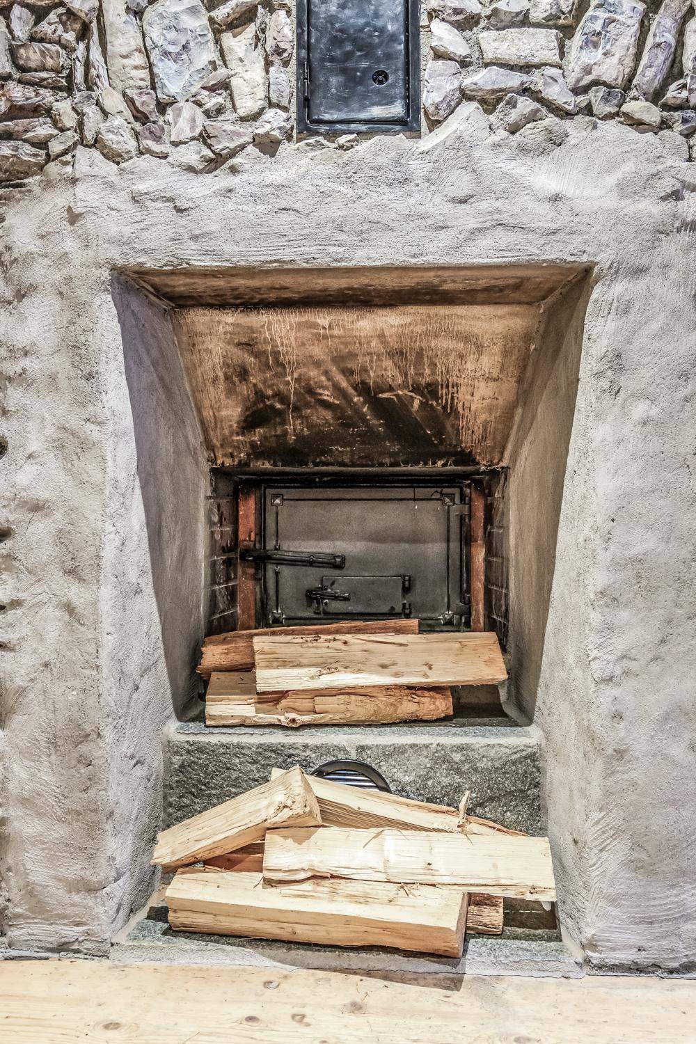 Traditioneller Kamin mit Holzscheiten und rustikaler Steinfassung, bereit zum Heizen.