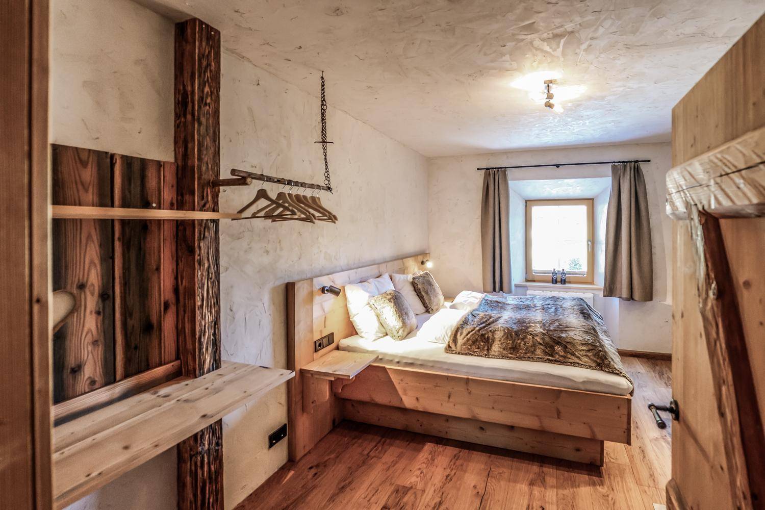 Helles Schlafzimmer mit Holzbett, integriertem Stauraum und einem Fenster für natürliches Licht.