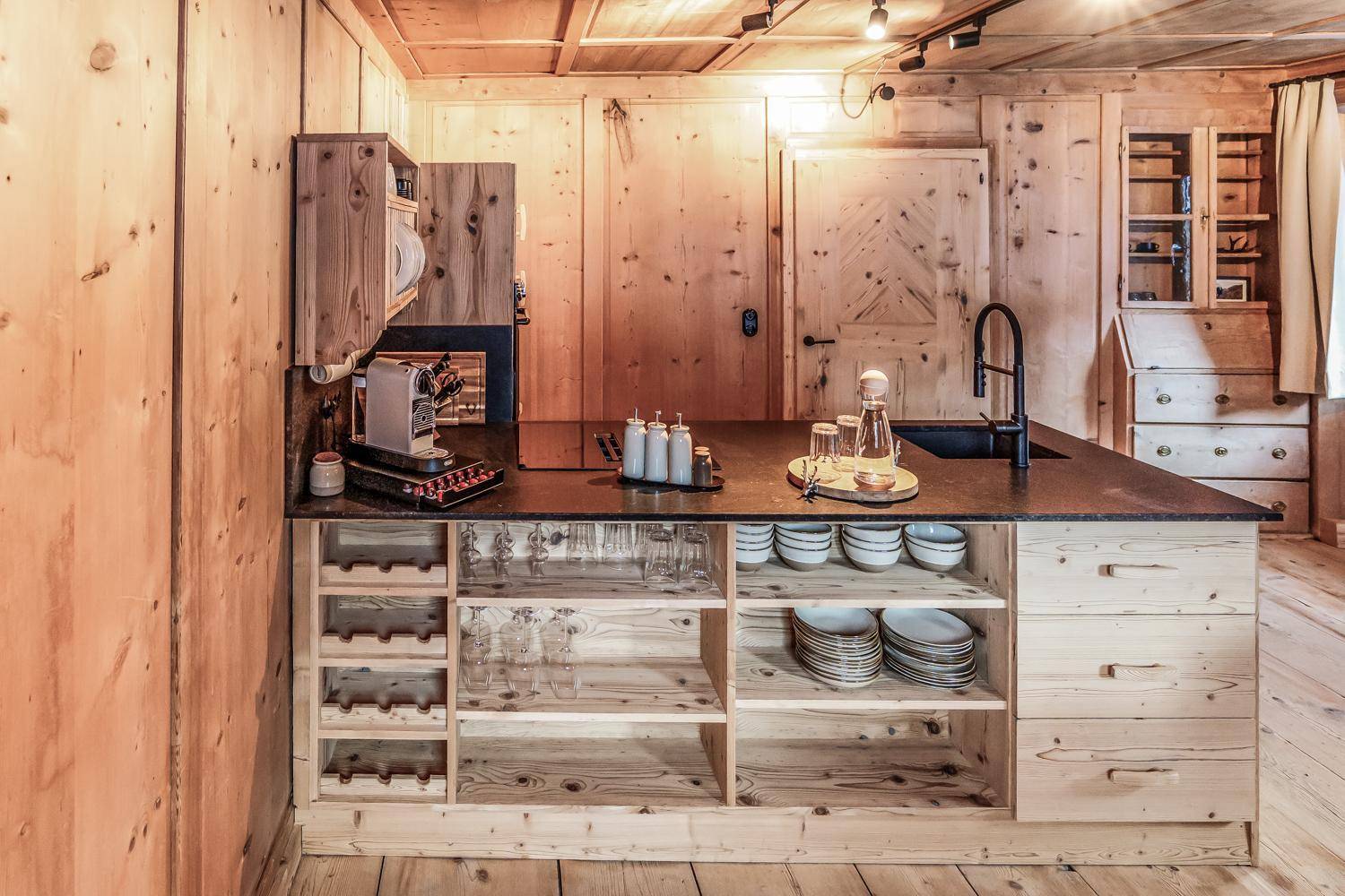 Rustikale Holzküche mit moderner Ausstattung, dunkler Arbeitsplatte und integrierter Kaffeemaschine.
