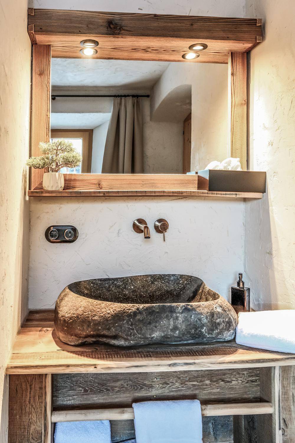 Rustikales Badezimmer mit einzigartigem Steinwaschbecken und Holzspiegelrahmen.