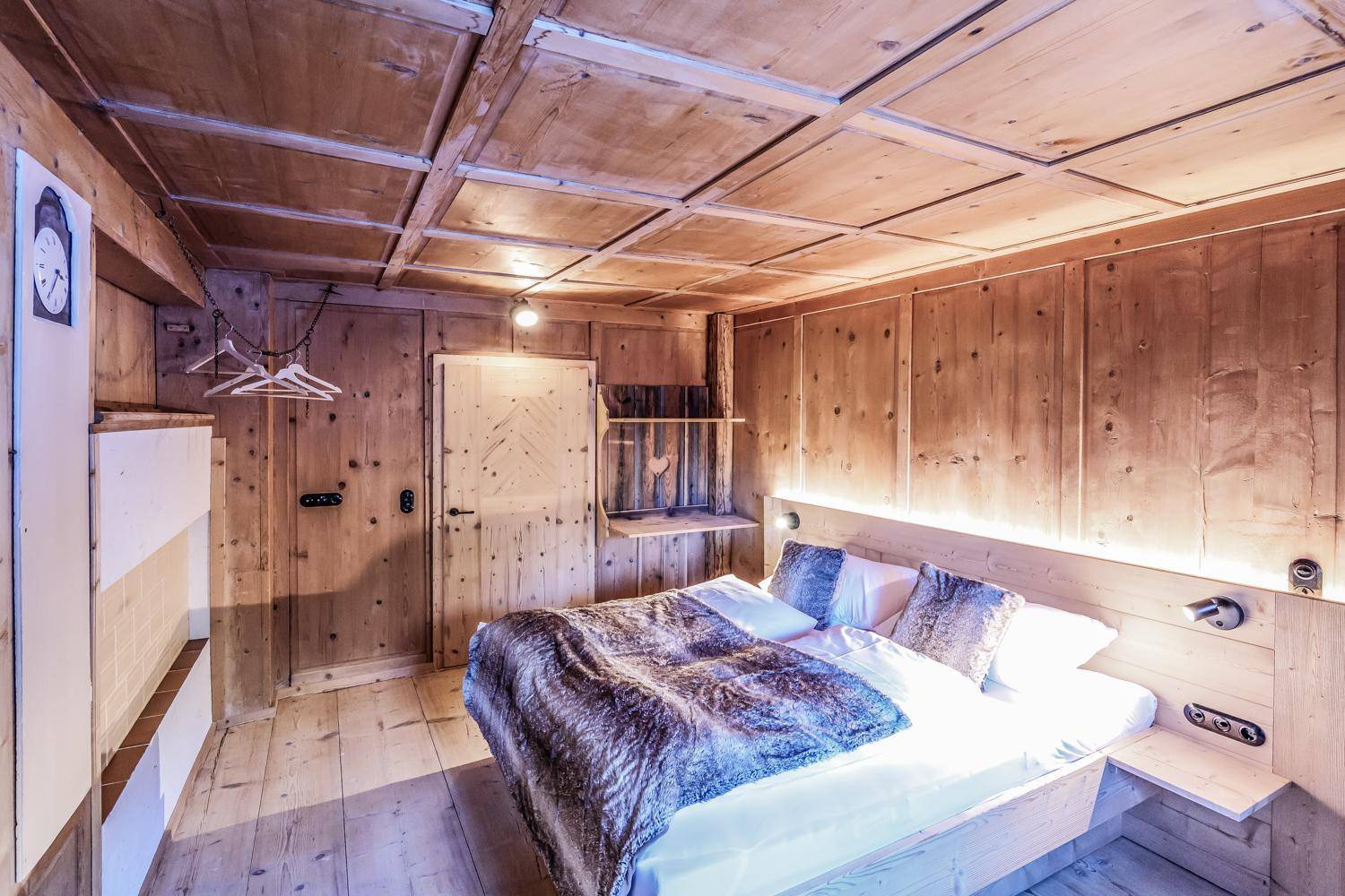 Gemütliches Schlafzimmer im alpinen Stil mit Holzwänden, Decken und einem großen Doppelbett.