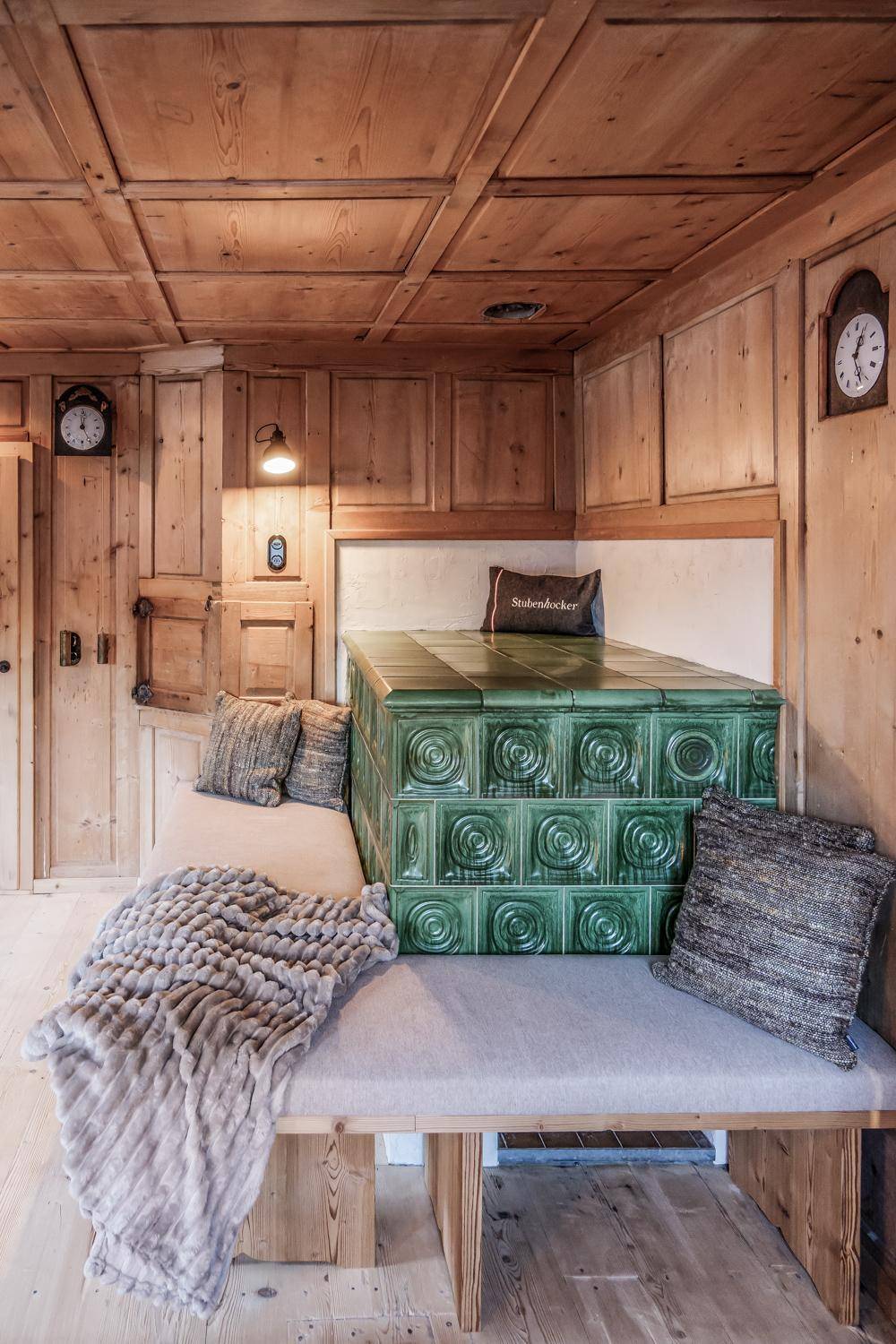 Gemütlicher Wohnbereich im alpinen Stil mit Holztäfelung und einem markanten grünen Kachelofen.