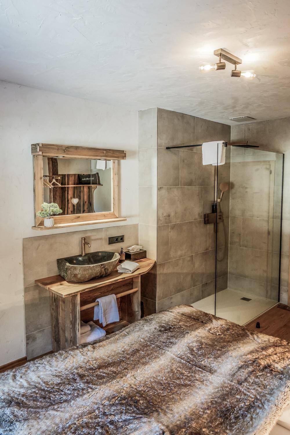 Schlafzimmer mit integriertem Steinwaschbecken und einer modernen, begehbaren Dusche.