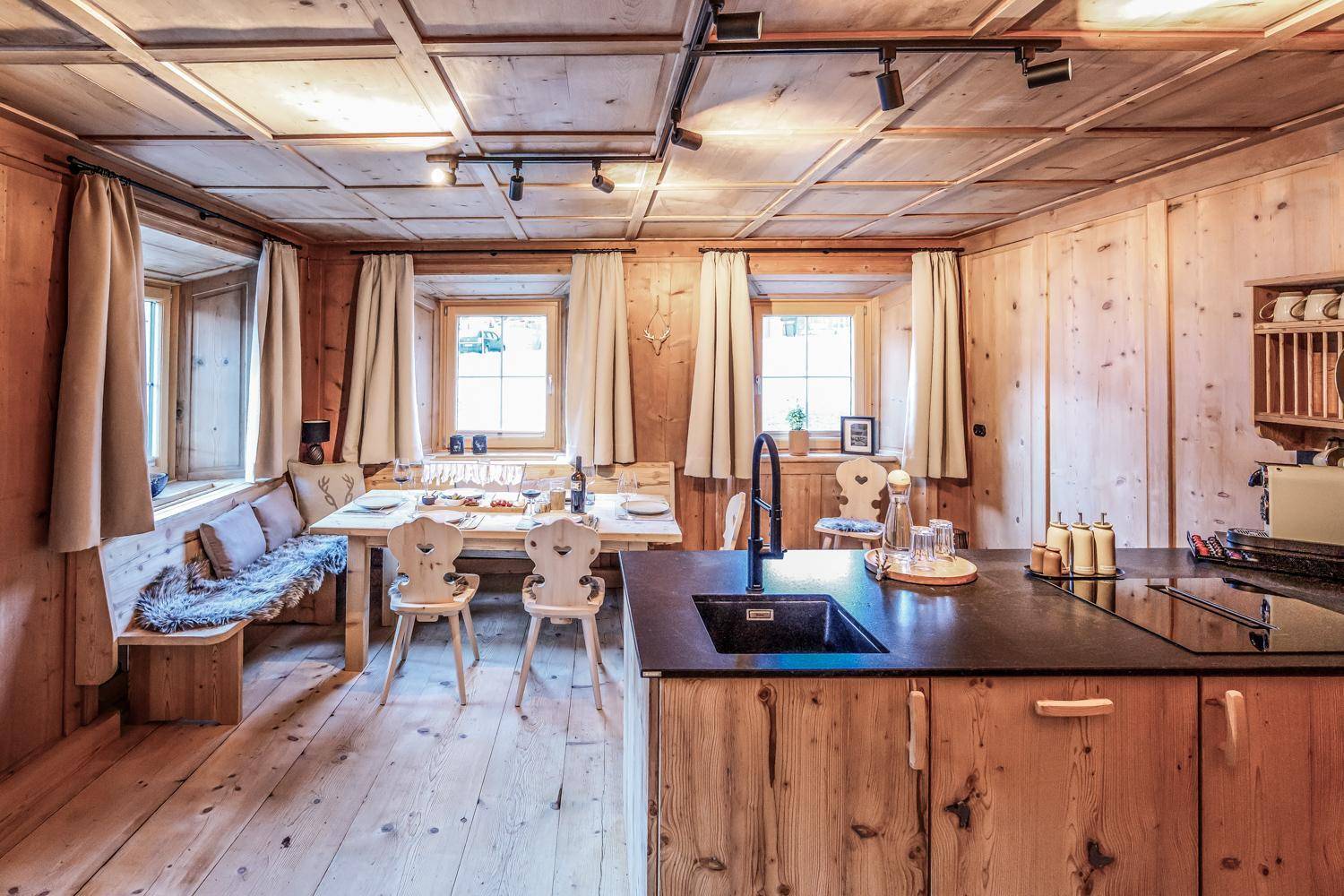 Gemütlicher Wohn-Essbereich im alpinen Stil mit Holztäfelung, Eckbank und traditionellen Stühlen.