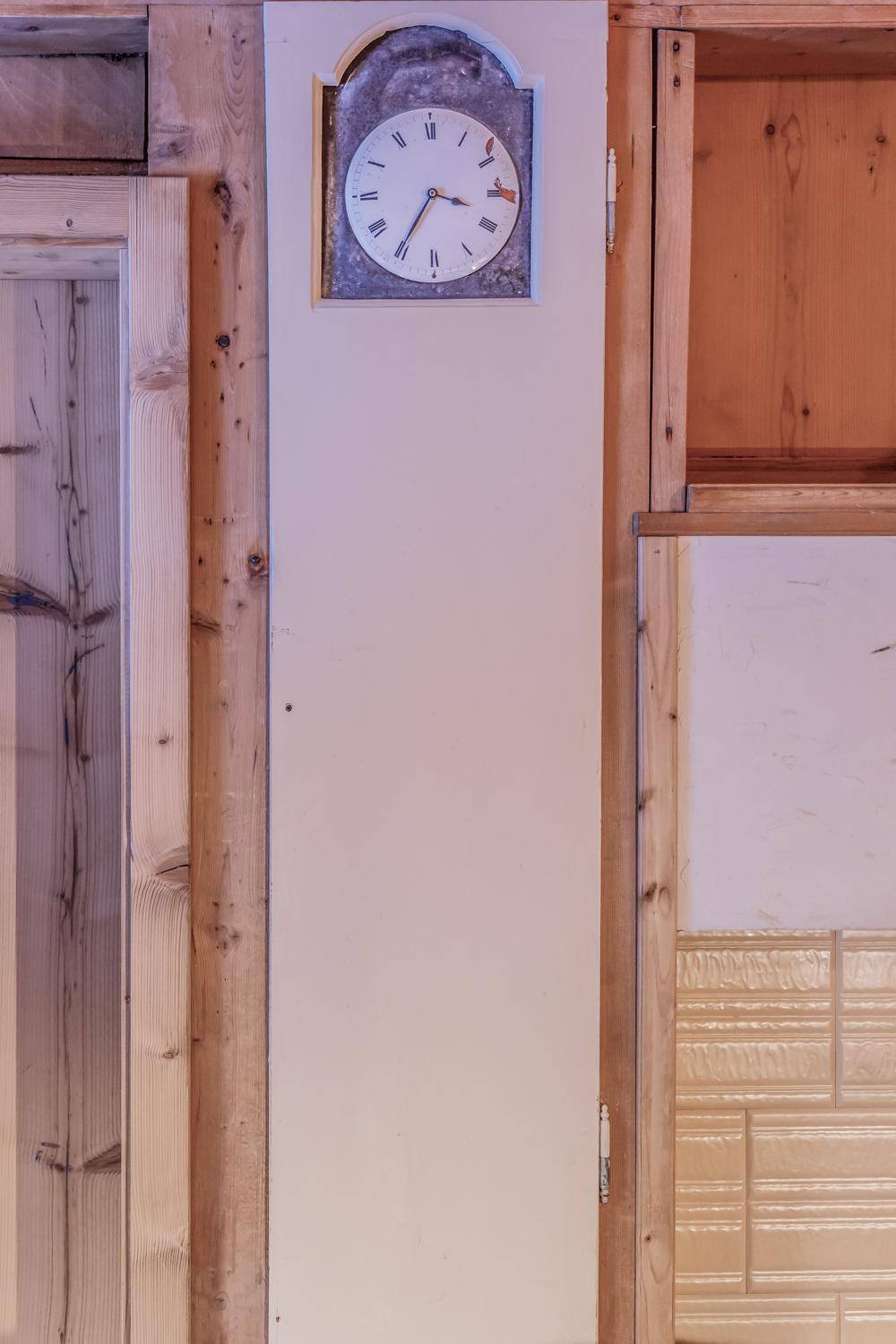 Detailaufnahme einer traditionellen Uhr, die elegant in eine Holzwand integriert ist.