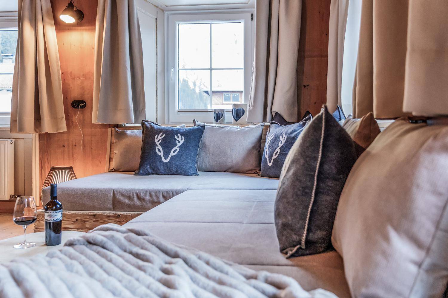 Komfortabler Wohnbereich mit großem Sofa, dekorativen Kissen und einem Fenster mit Ausblick.