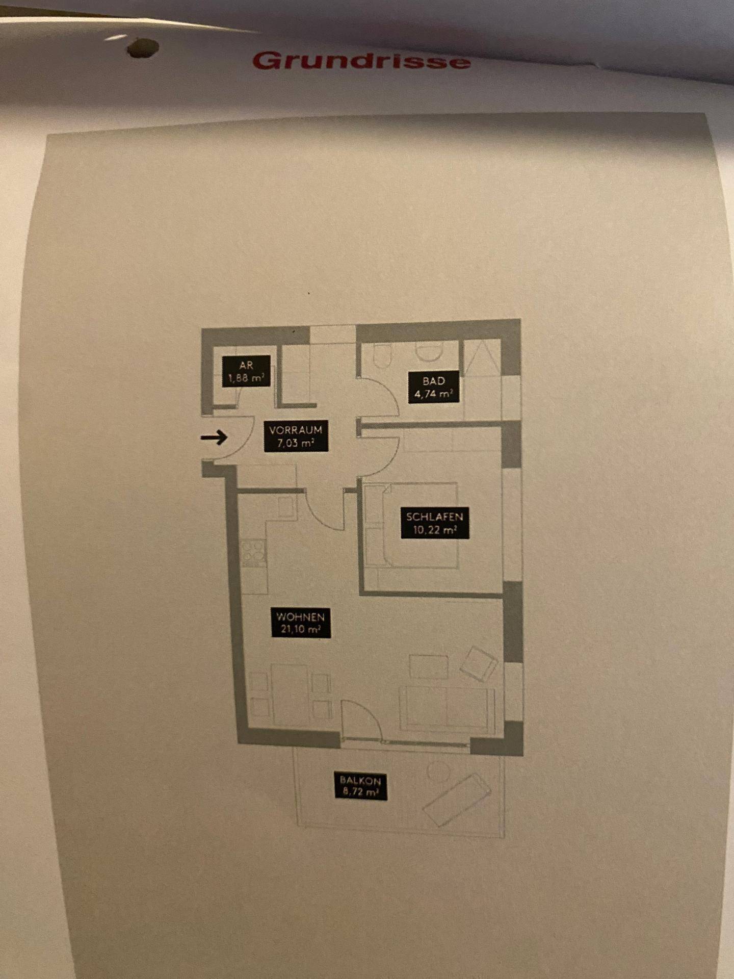 Grundriss einer Wohnung mit Schlafzimmer, Wohnbereich, Bad und Balkon.