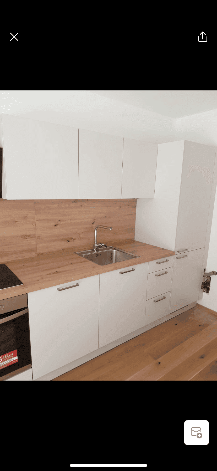 Detailansicht der neuen Einbauküche mit Spüle, Herd und weißen Schränken.