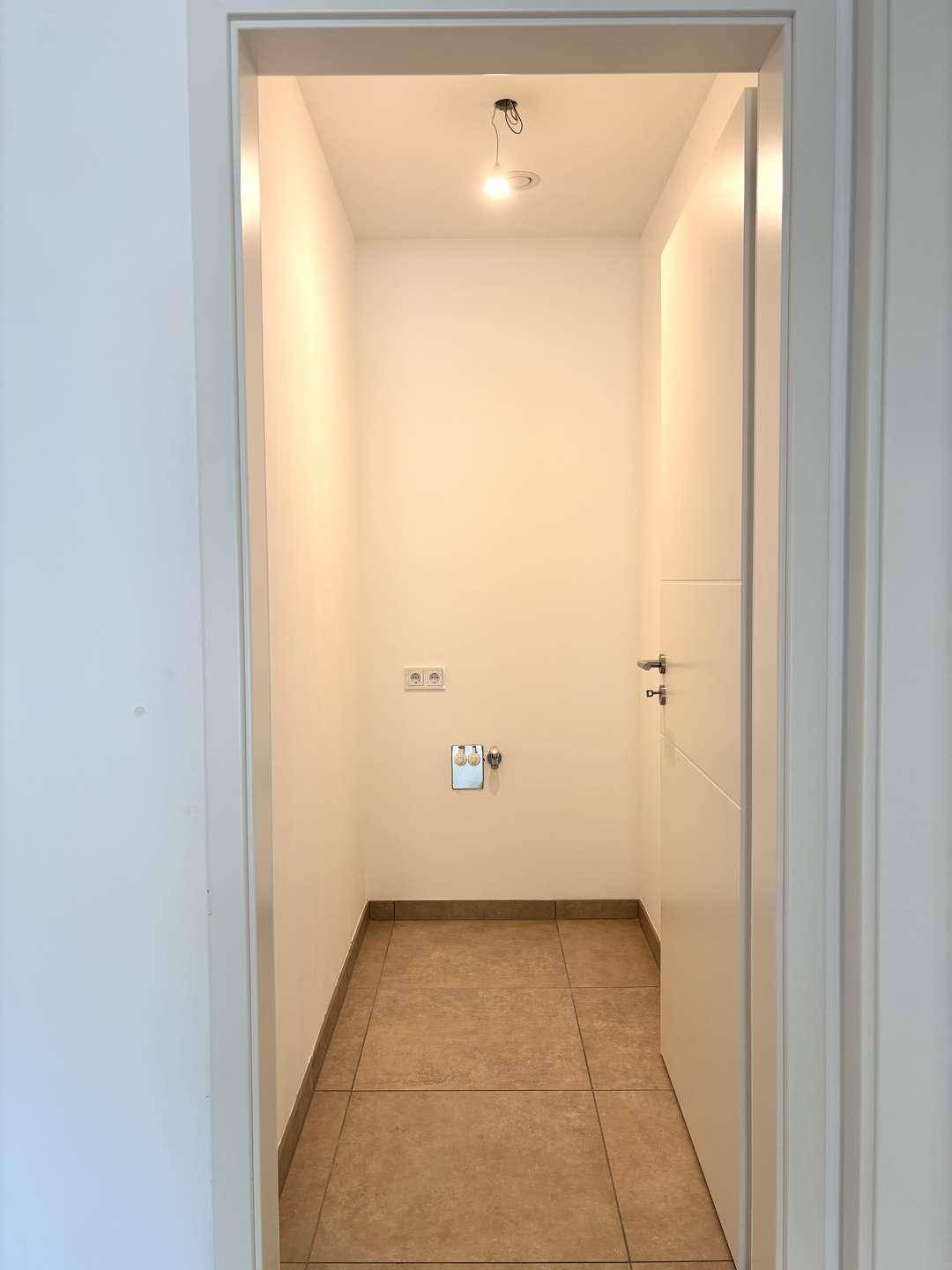 Praktischer Hauswirtschaftsraum mit Fliesenboden und Anschlüssen für Waschmaschine und Trockner.