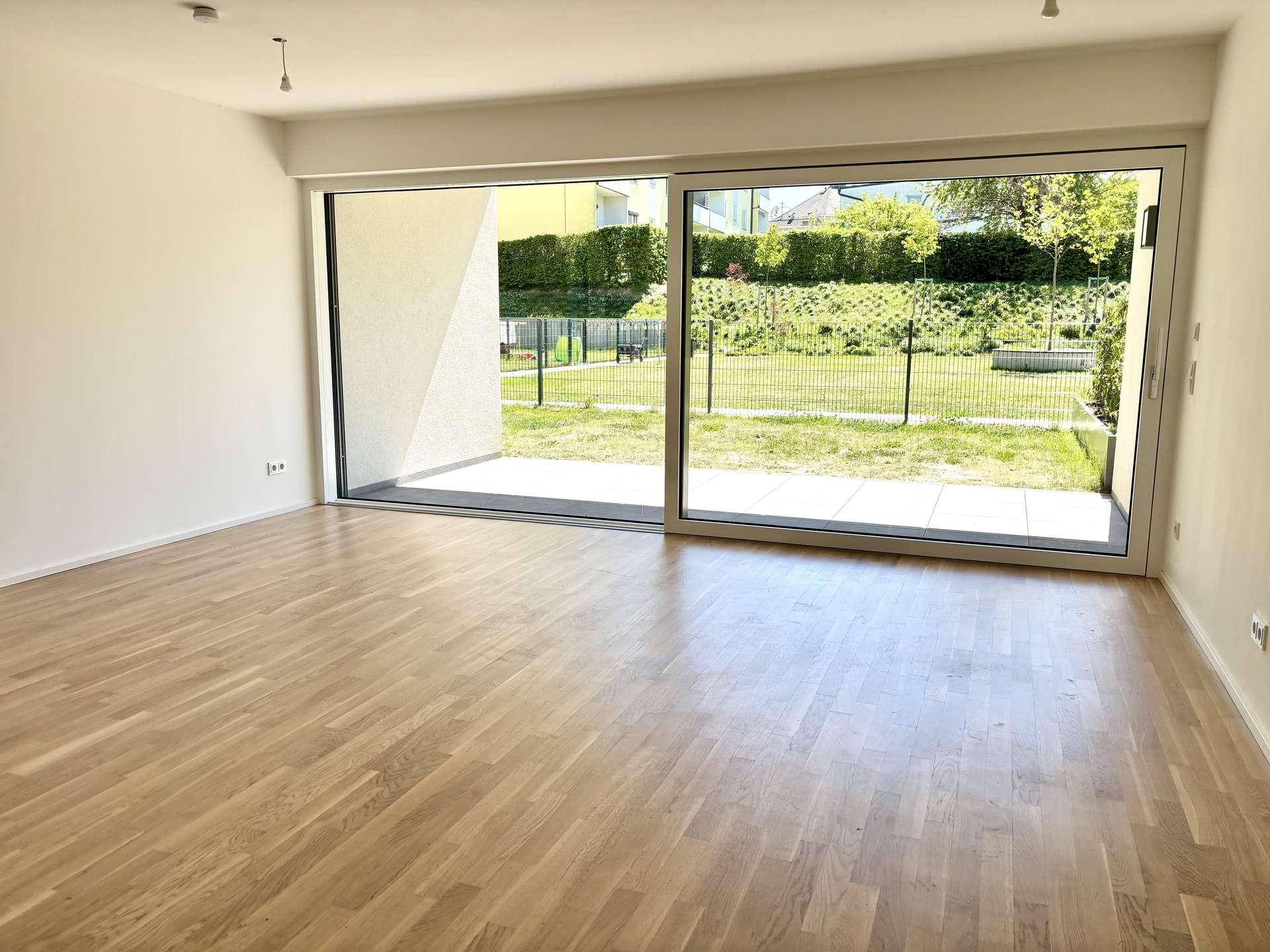 Lichtdurchfluteter Wohnbereich mit großen Schiebetüren, die Zugang zu einer Terrasse und dem Garten bieten.
