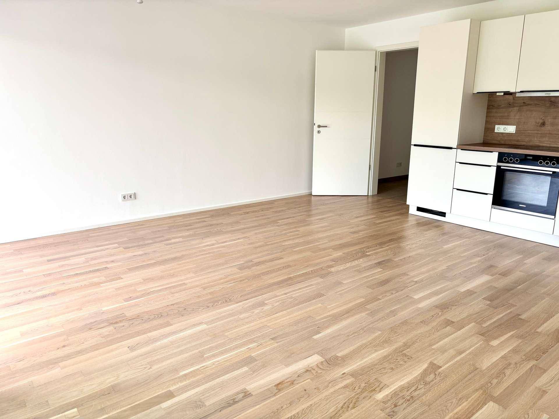 Heller, leerer Wohnbereich mit neuem Parkettboden und viel Platz für individuelle Gestaltung.