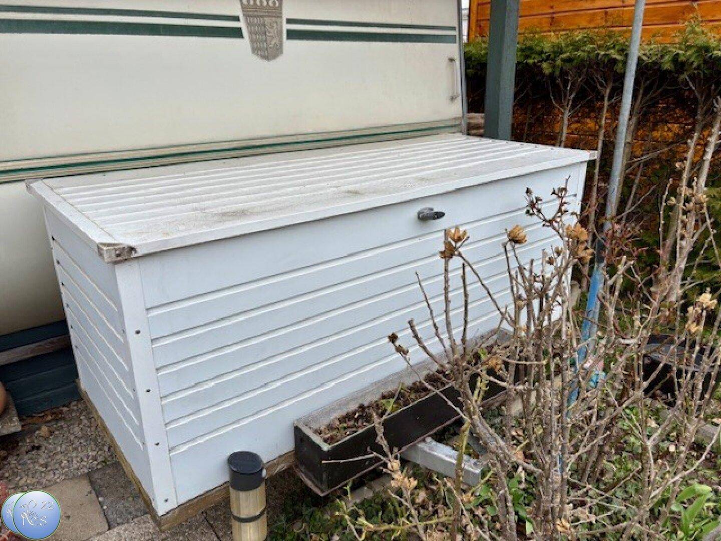 Weiße Outdoor-Aufbewahrungsbox neben dem Wohnwagen im Außenbereich.